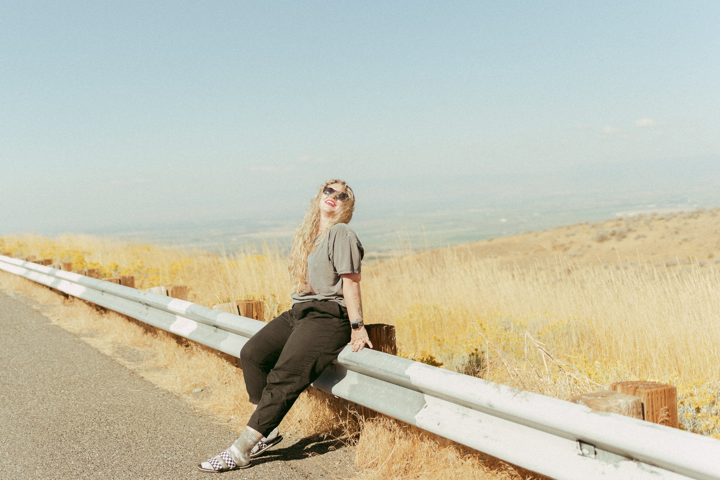 Wedding photographer Ashley Seagle standing fiercely among the golden, windswept hills between Seattle and Yakima—embodying the raw, untamed energy of the Pacific Northwest. Washington state elopement photographer vibes meet Wild West spirit.