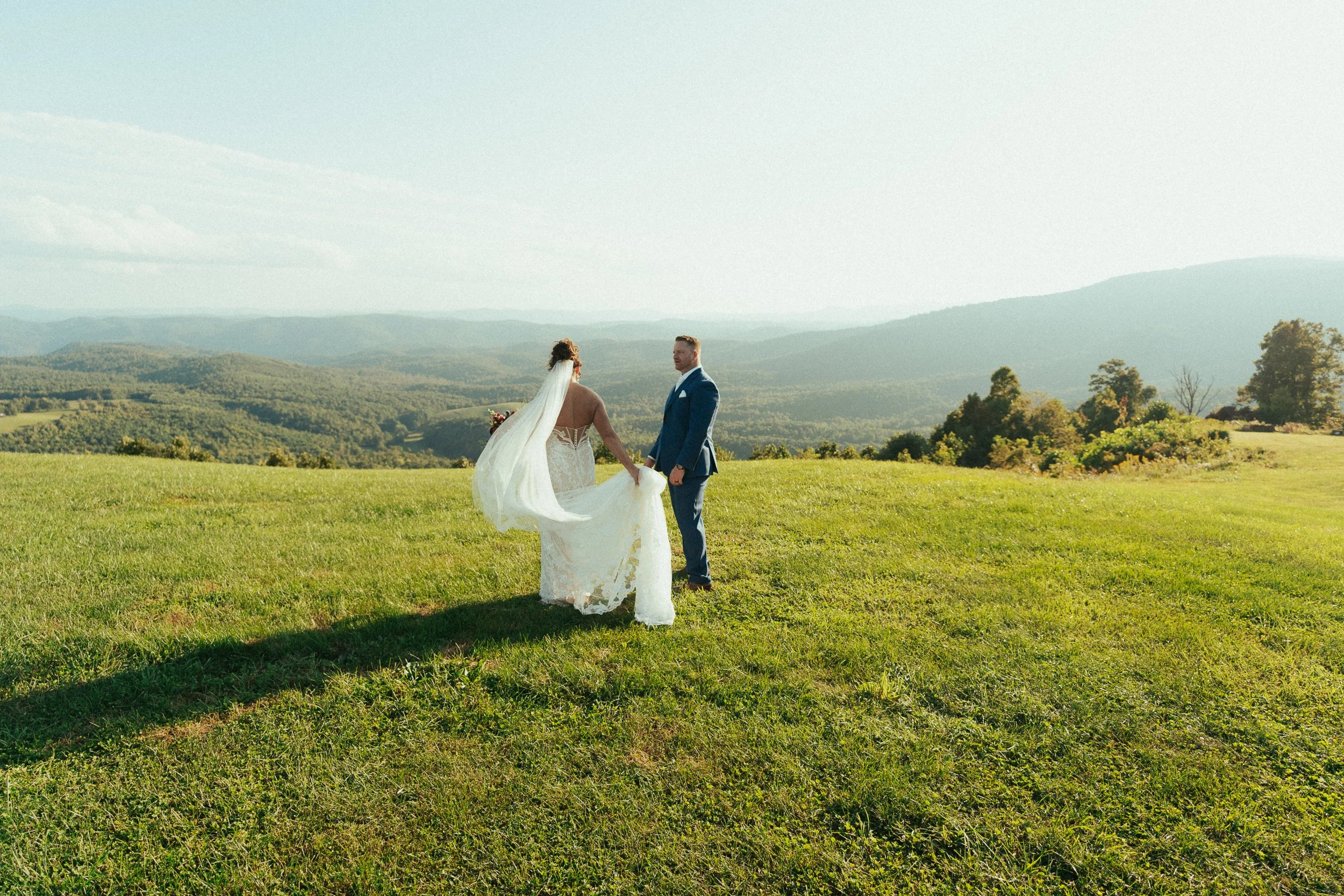 Couple sharing a quiet in-between moment on a hillside overlooking the Blue Ridge Mountains at Sky Retreat in Purlear, NC | emotional documentary wedding photography
