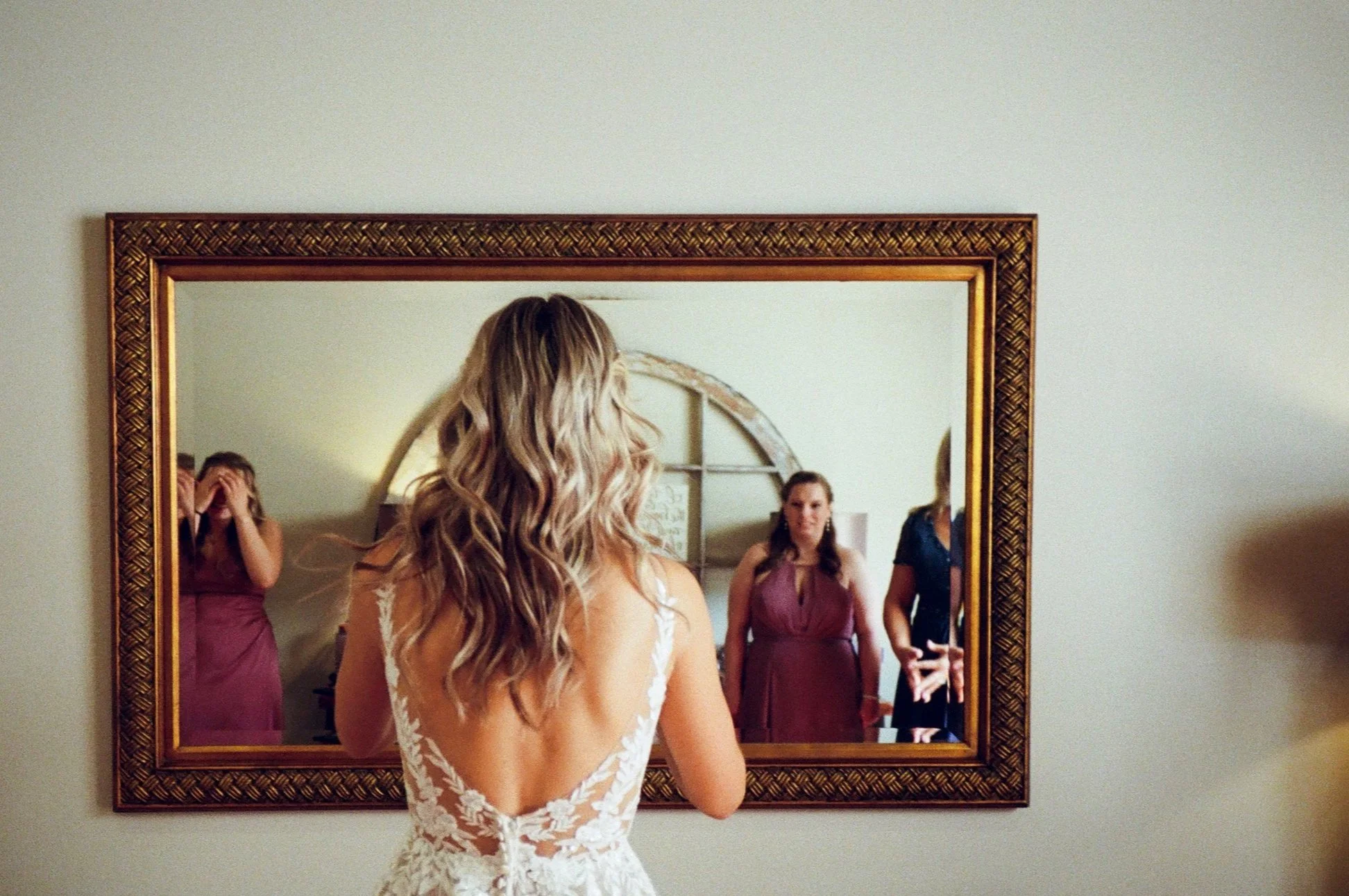 stunning Kodak portra 400 image of the bride looking in the mirror to finish up getting ready at the venue cross & main in youngsville, nc