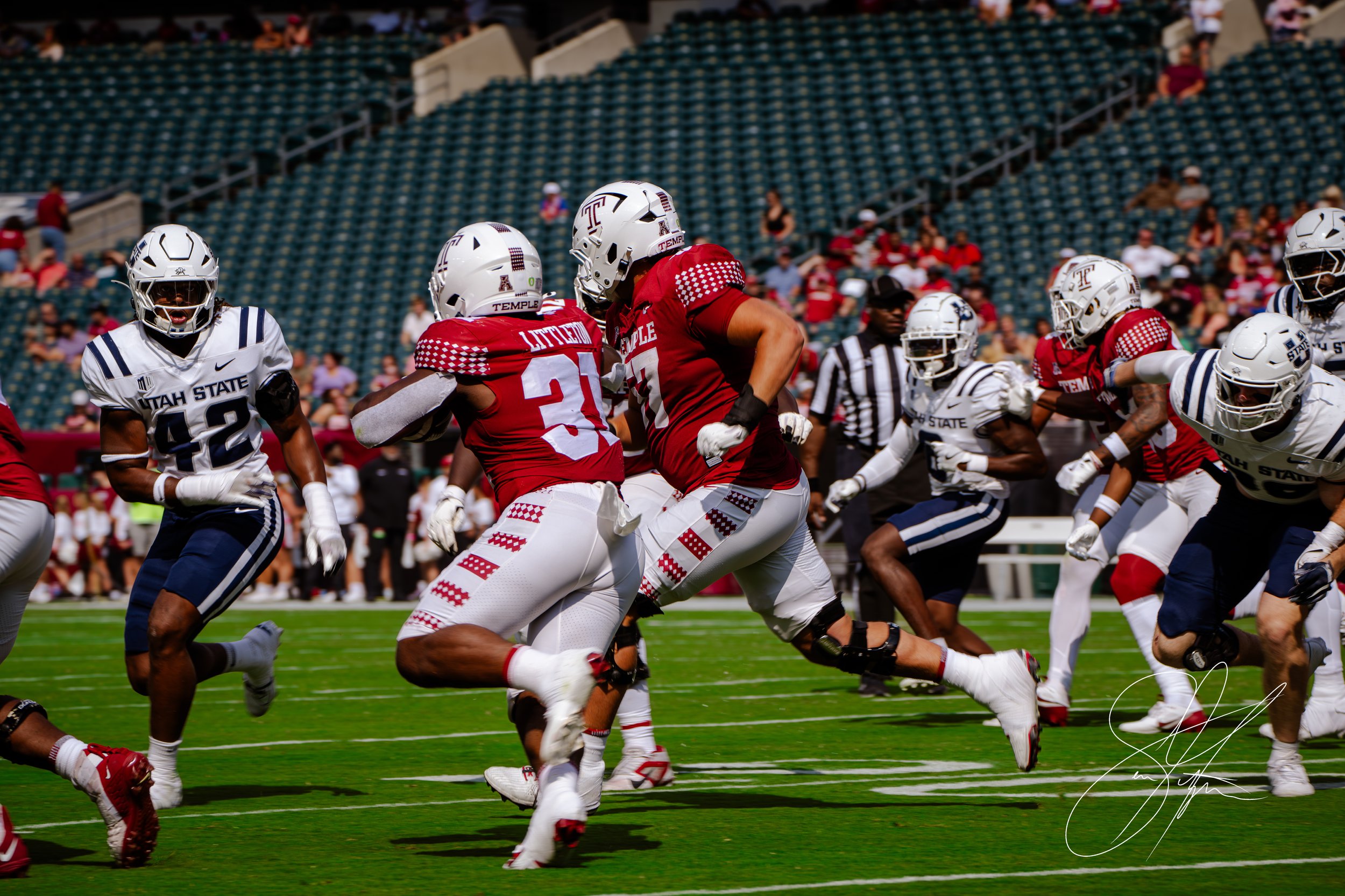 College football game with Temple and Utah State players in action on the field.