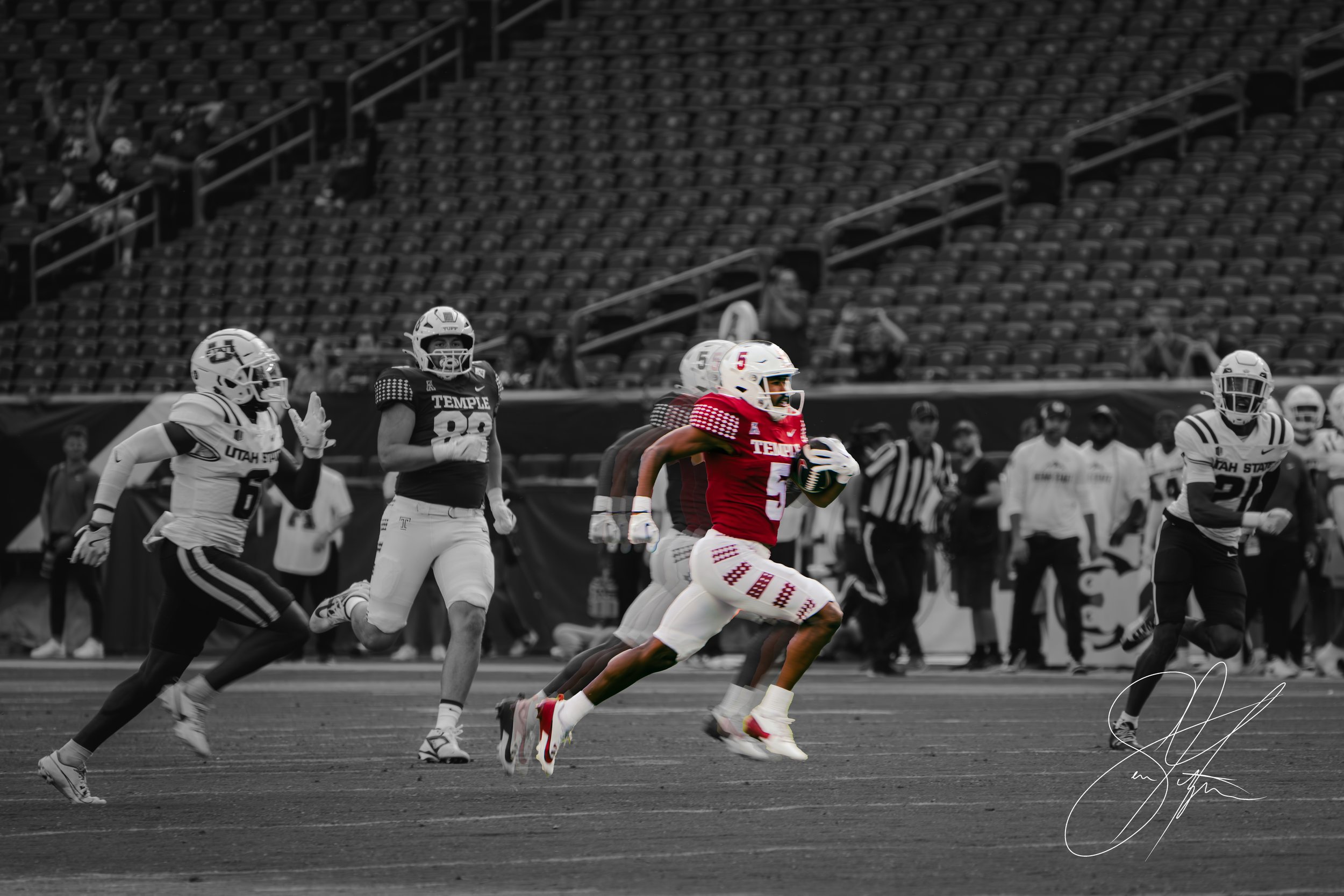 Football game with Temple University player running while holding the ball, pursued by Utah State players. The player in focus is in color, while the background is black and white.