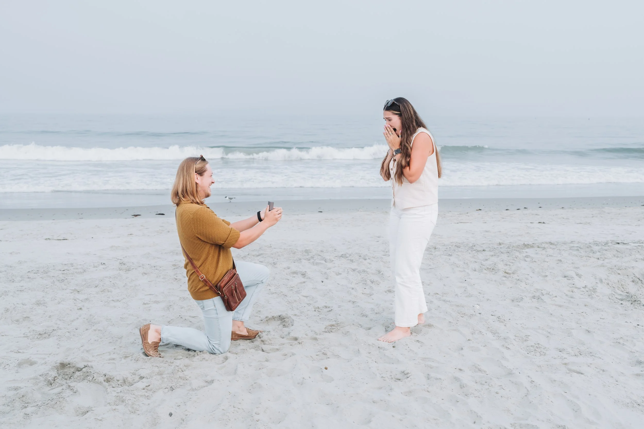 Person proposing on a beach with ocean waves in the background