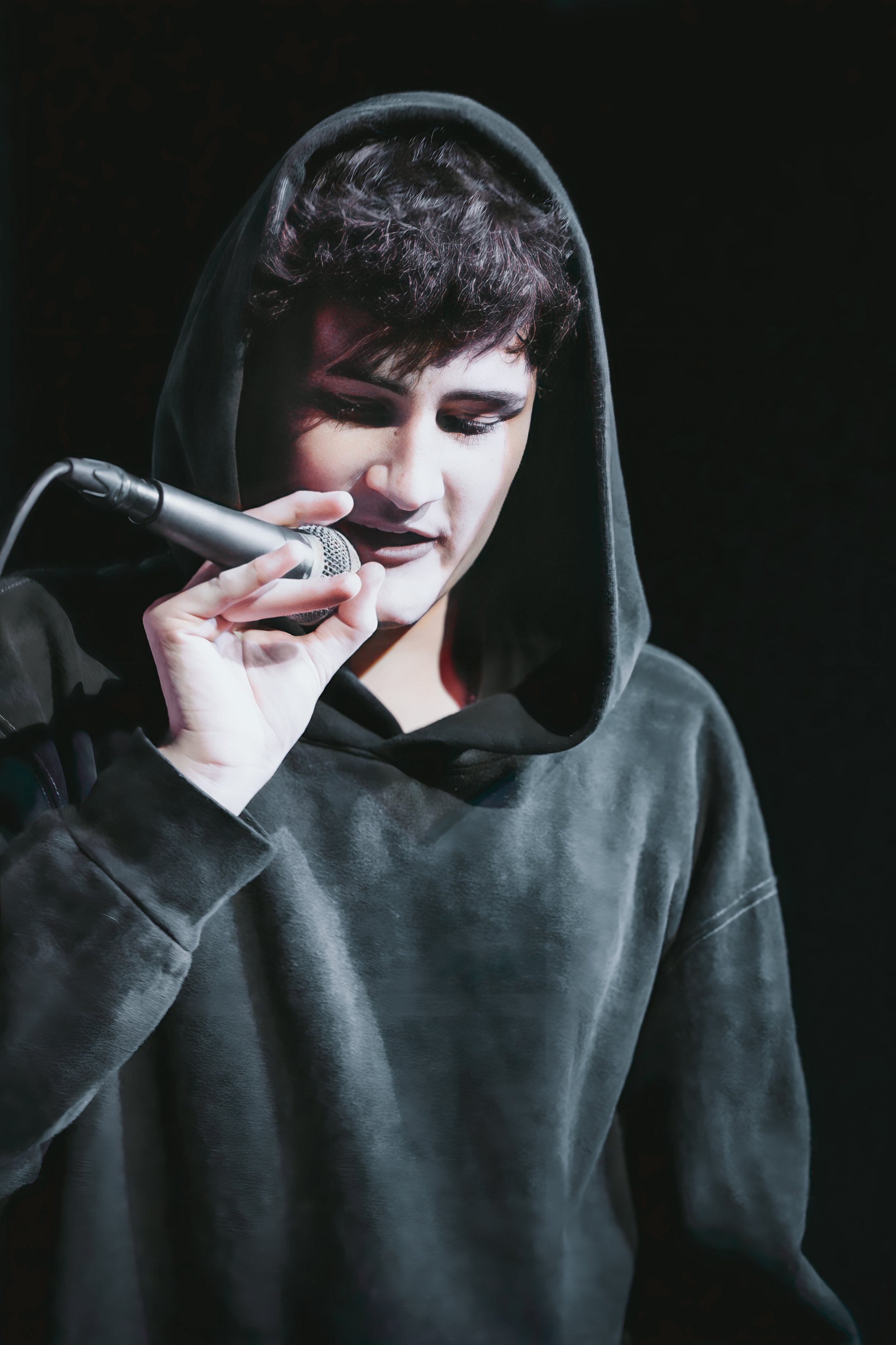 Person wearing a hoodie holding a microphone on stage