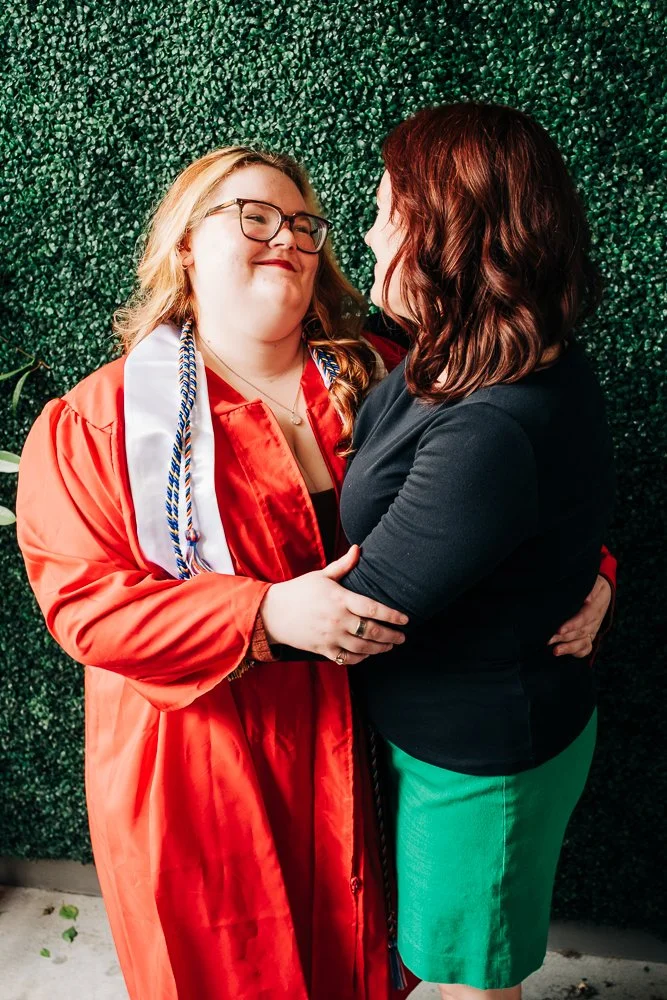 Photographer, Libby Dollar, embraces her daughter, Alessi, who is wearing her high school graduation robes