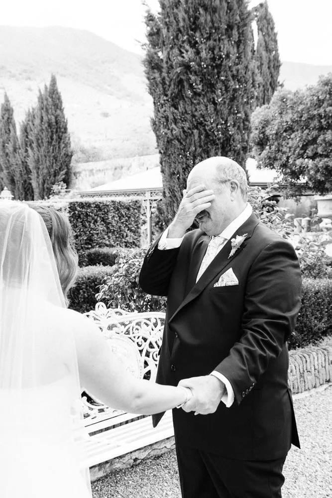 A bride's dad holds back tears as he sees her in her wedding dress for the first time