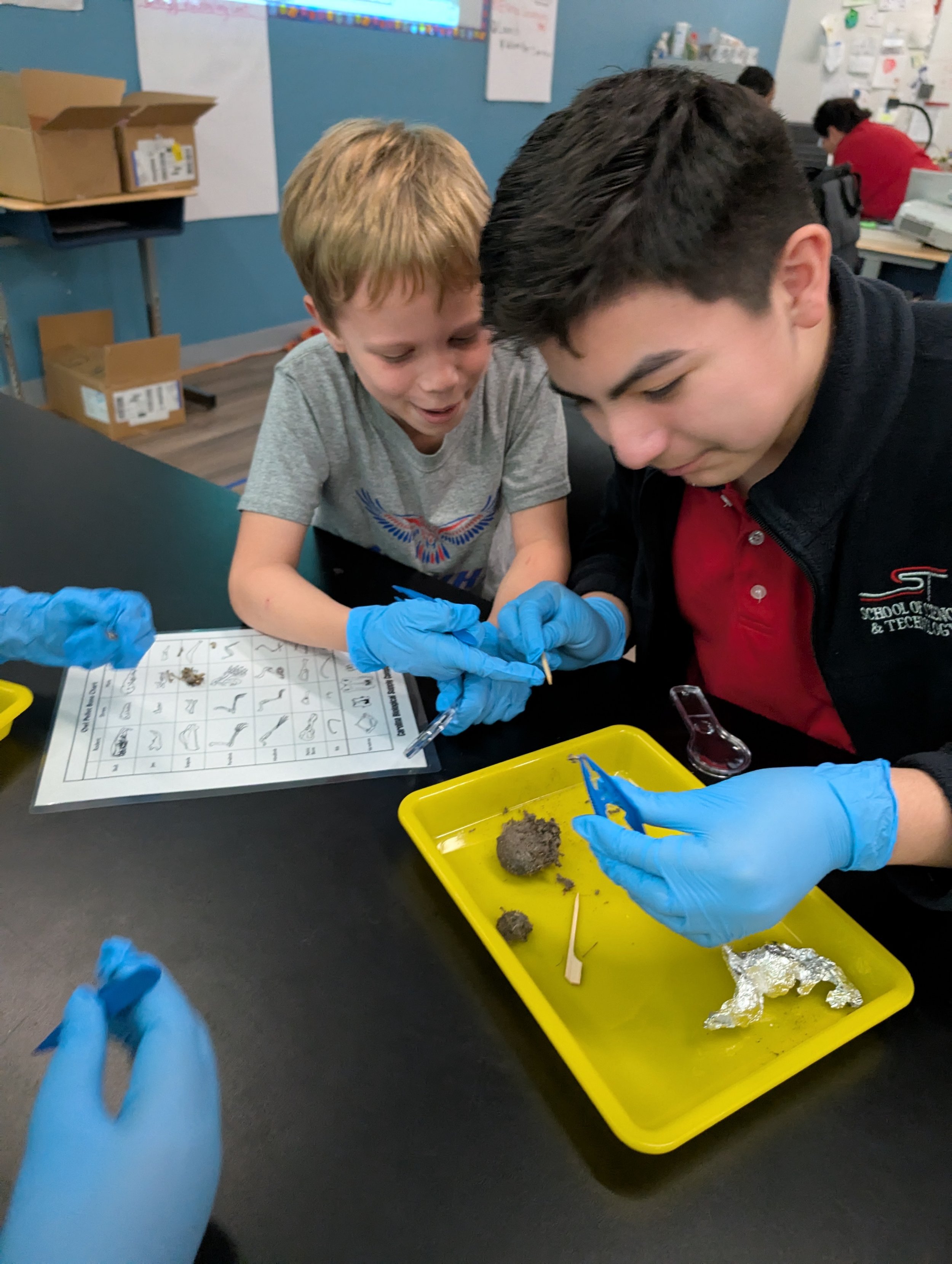 two boys smiling while dissecting owl pellets