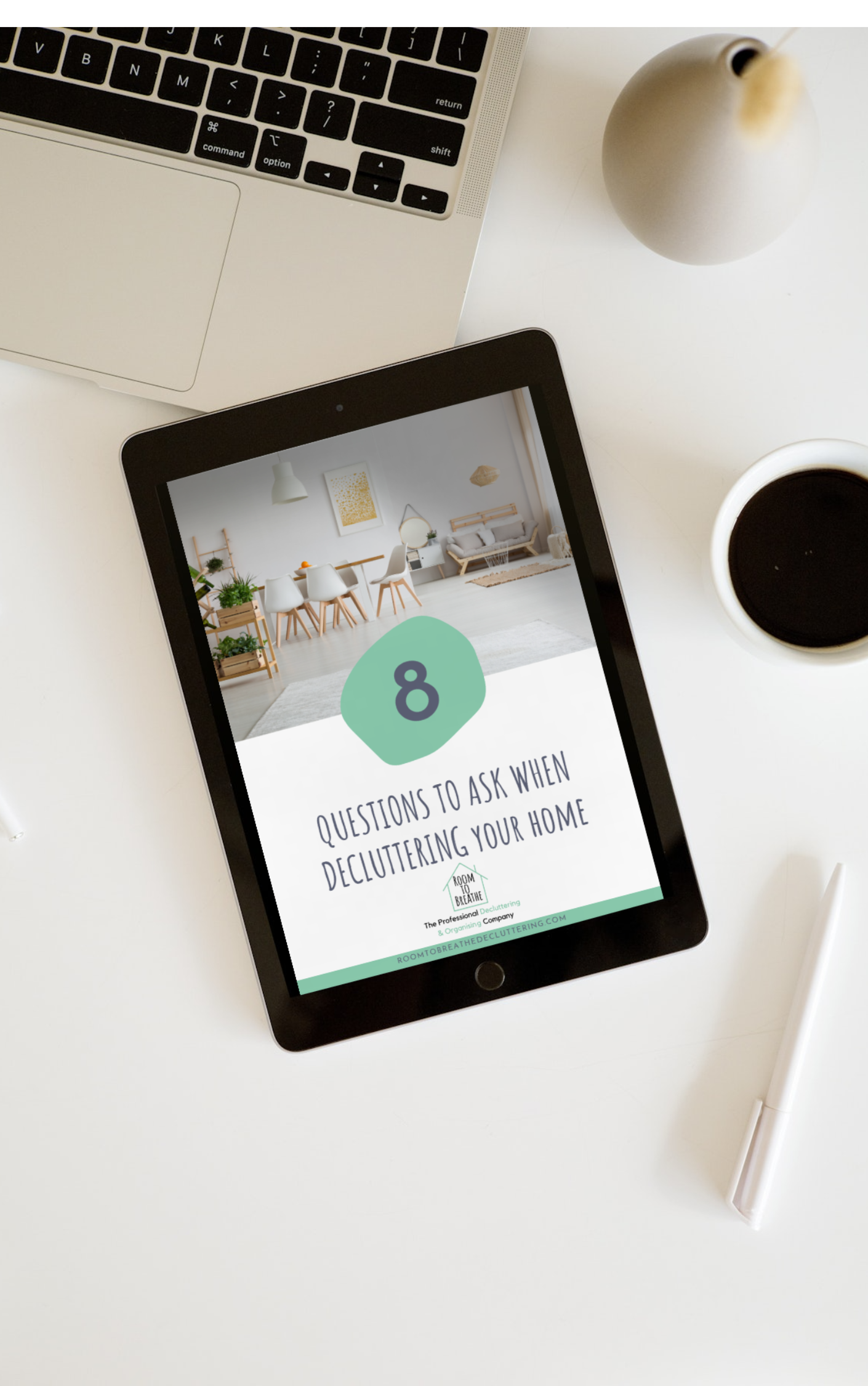Tablet displaying '8 Questions to Ask When Decluttering Your Home' guide, on a desk with a laptop, pen, coffee, and vase.