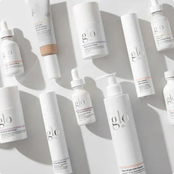Various skincare products in white bottles and containers with minimalist labels, arranged on a white surface.
