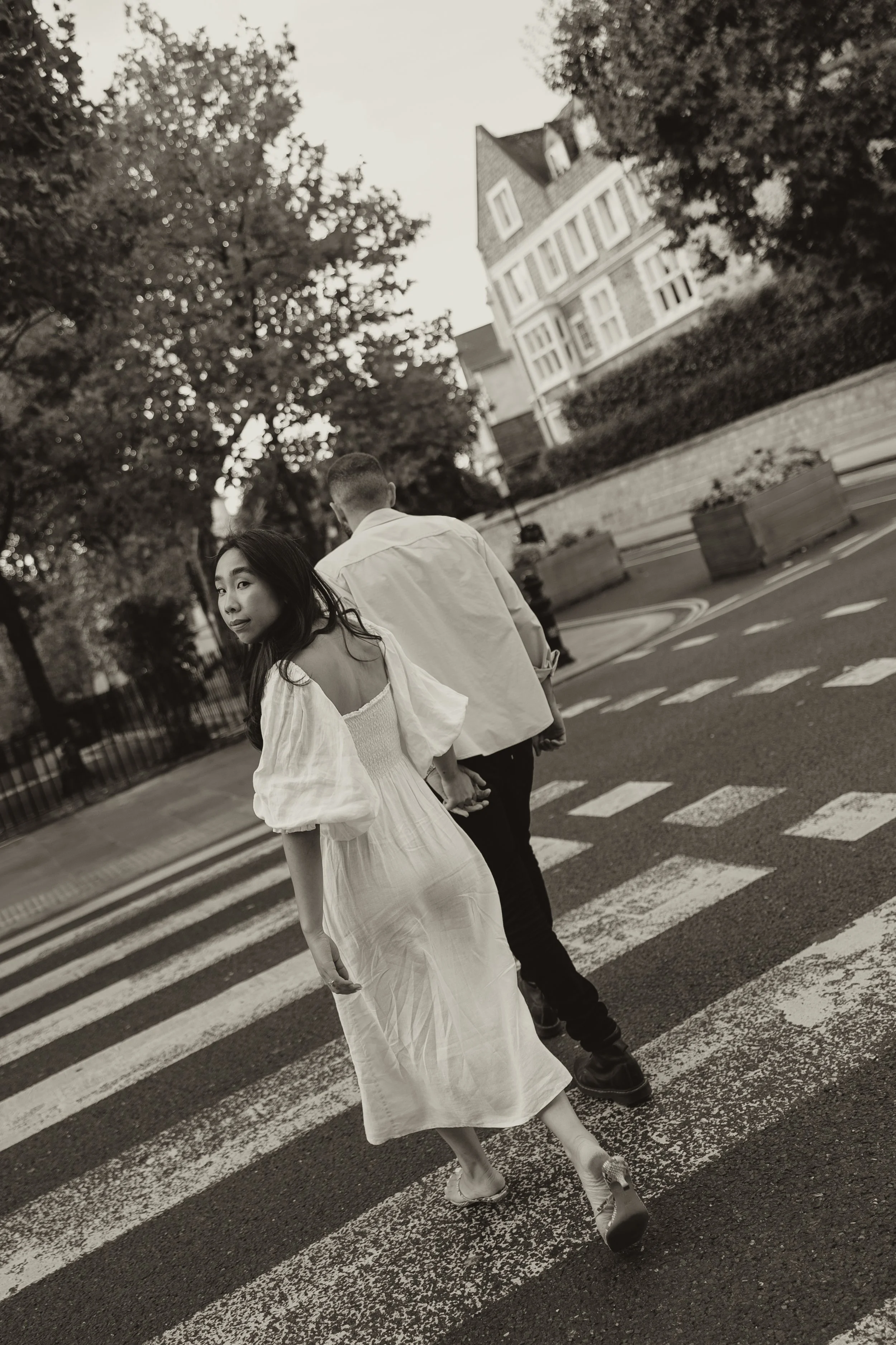 Couple walking over pedestrian crossing in London during a pre-wedding photoshoot in the UK, captured in an editorial wedding photography style