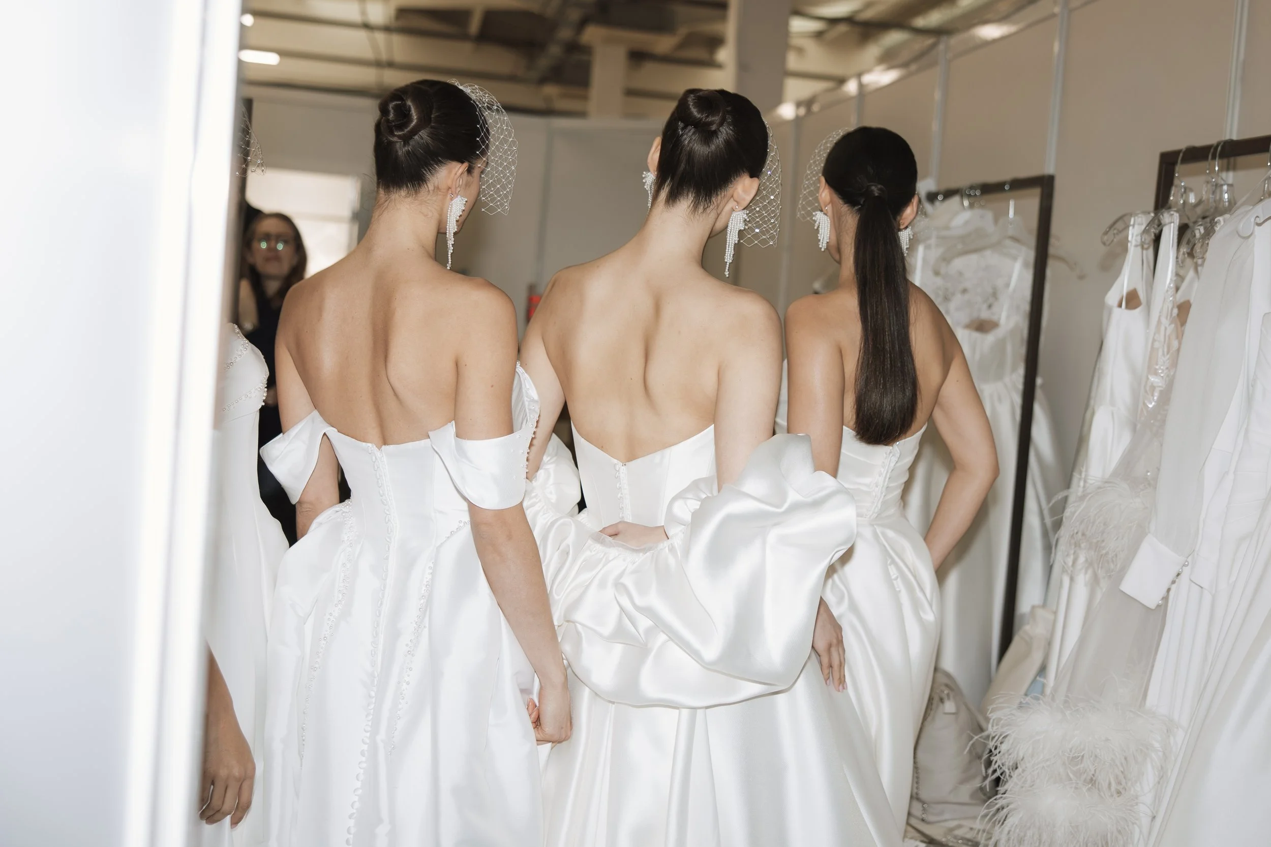 Backstage at London Bridal Fashion Week with models in structured satin wedding dresses captured in an editorial style