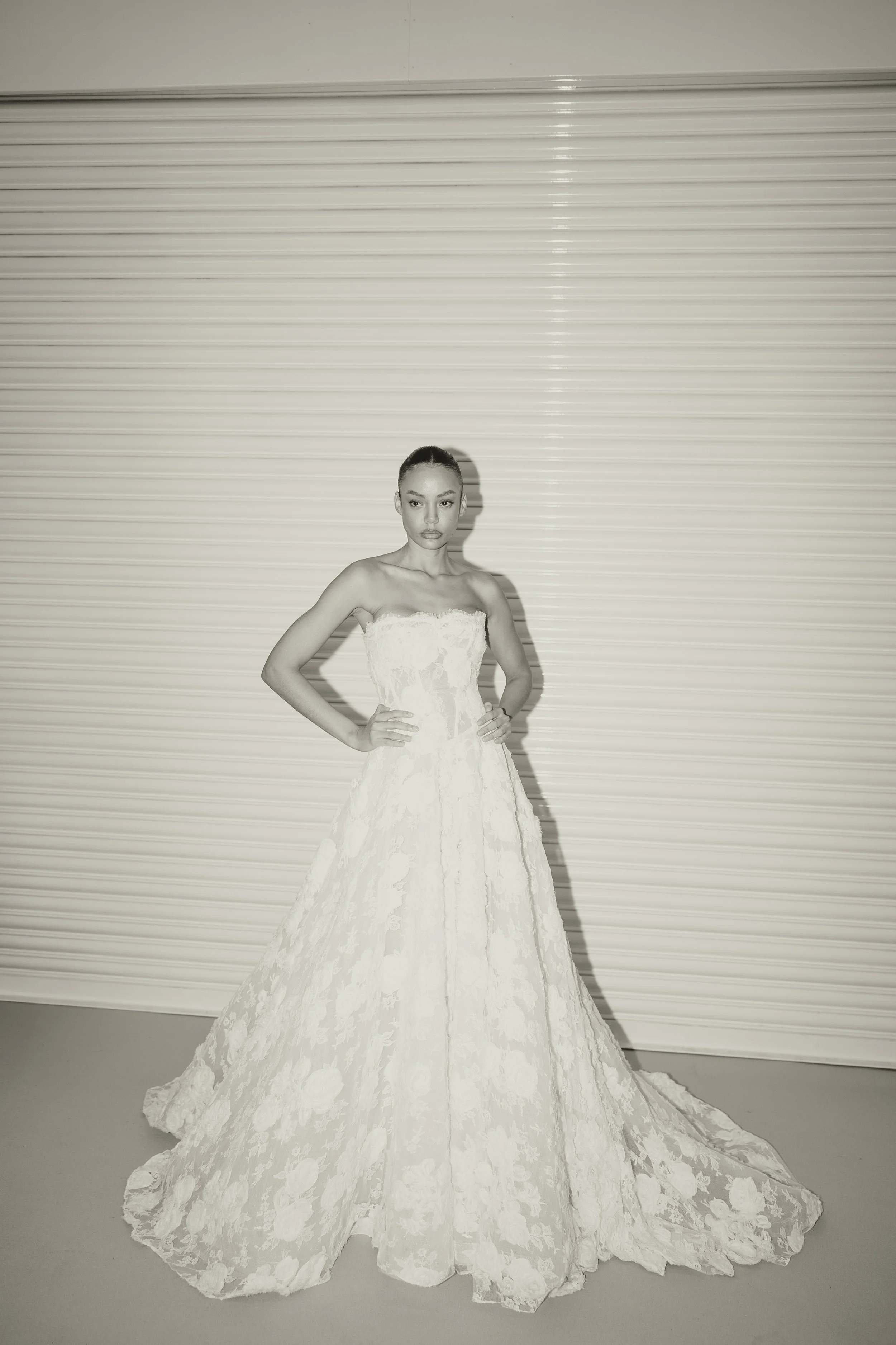 Editorial bridal portrait of a modern bride in a structured lace wedding dress, captured in a fashion-inspired style with clean, minimal backdrop