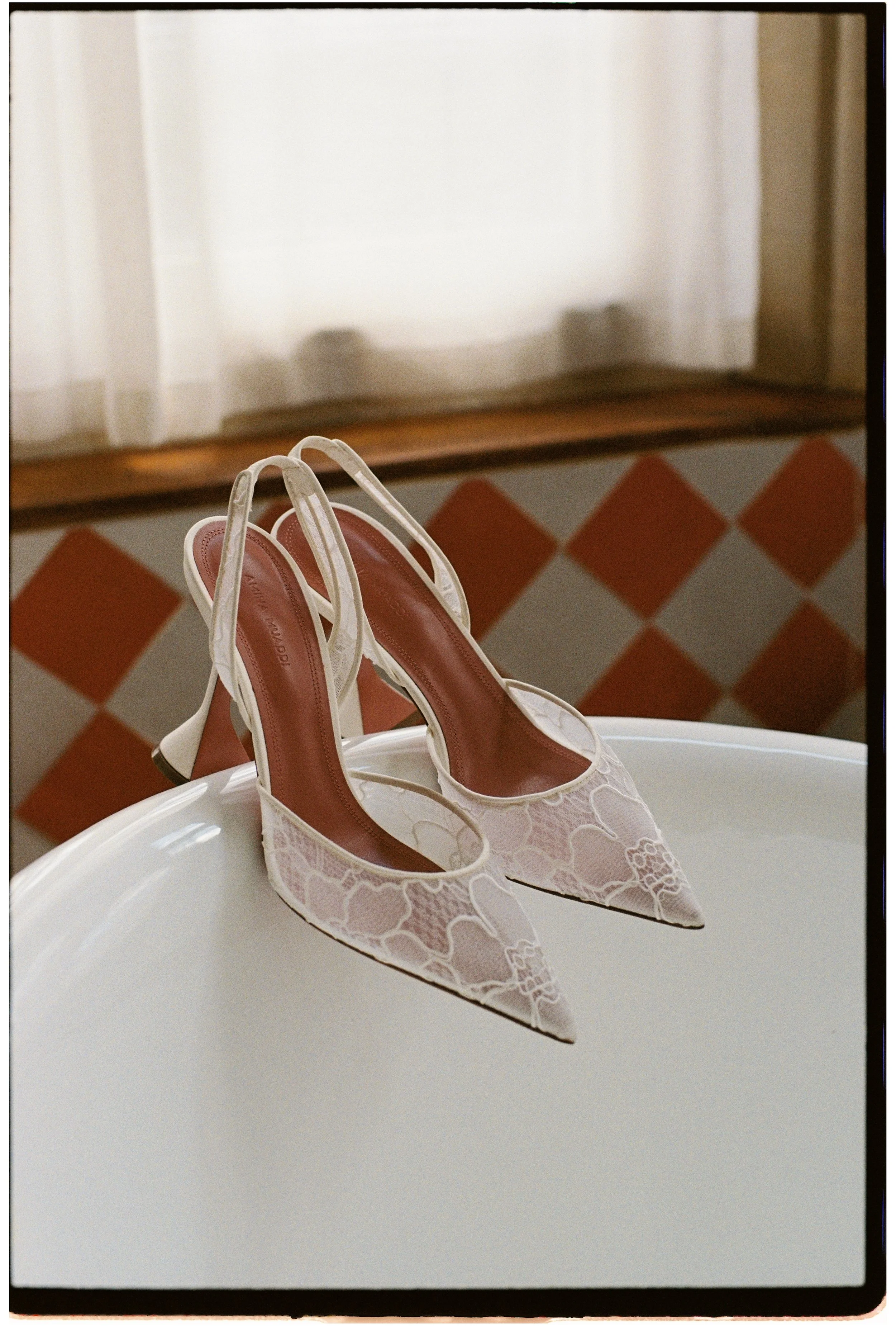 Editorial bridal shoes photographed on 35mm film at Kin House, featuring lace slingback wedding heels styled on a freestanding bath.