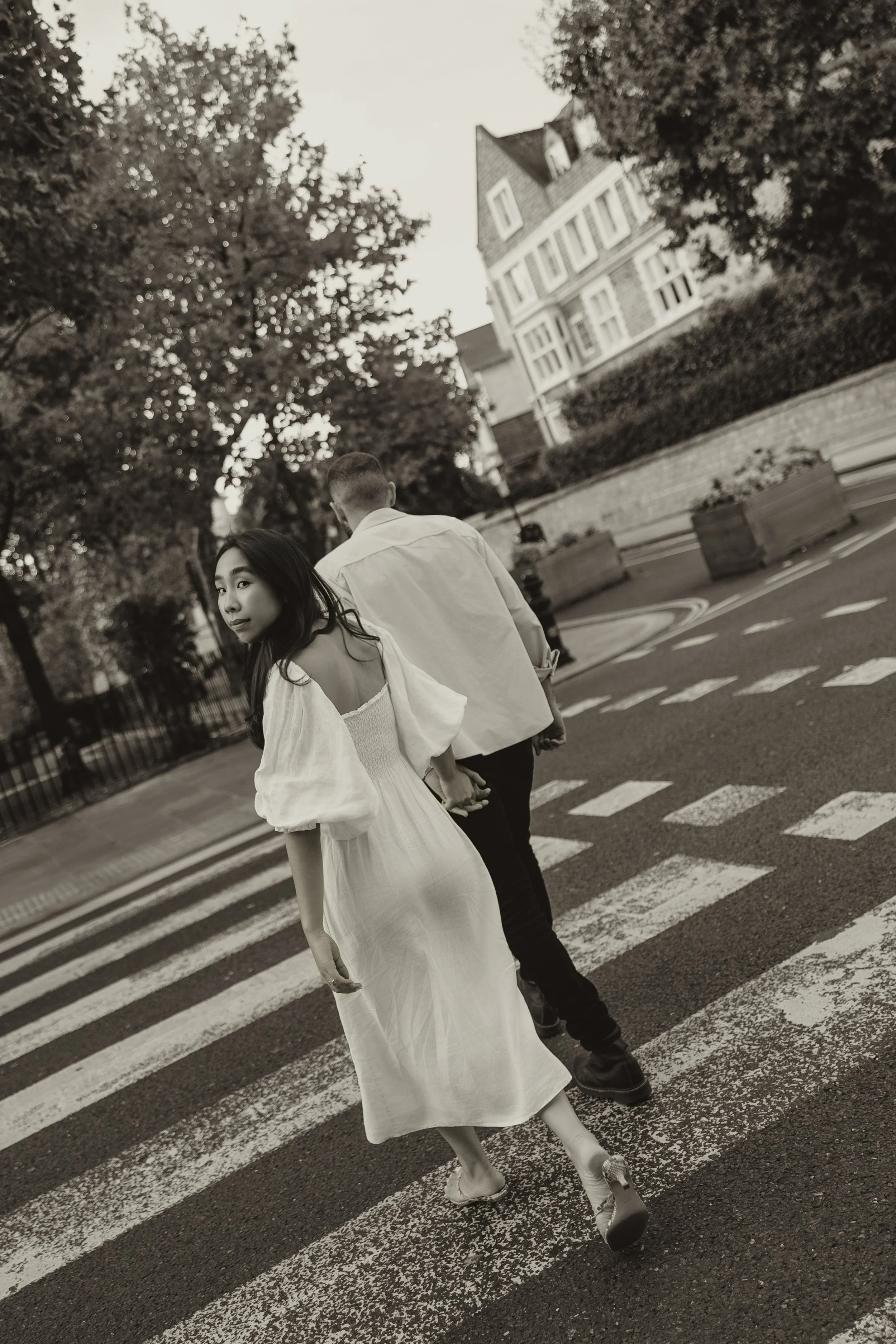 Stylish couple holding hands while crossing a London street during an editorial pre-wedding shoot, captured in a candid, fashion-inspired moment.