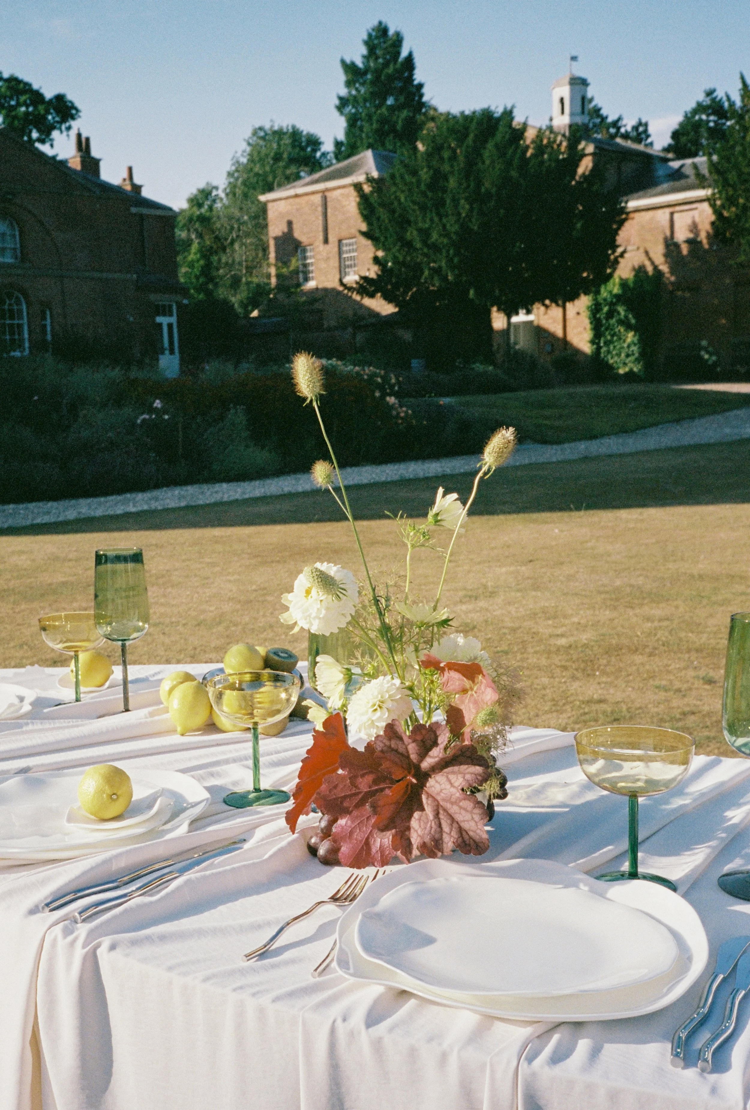 Floral arrangement on wedding breakfast table outside at Norwood Park photographed on 35mm film with muted, romantic tones