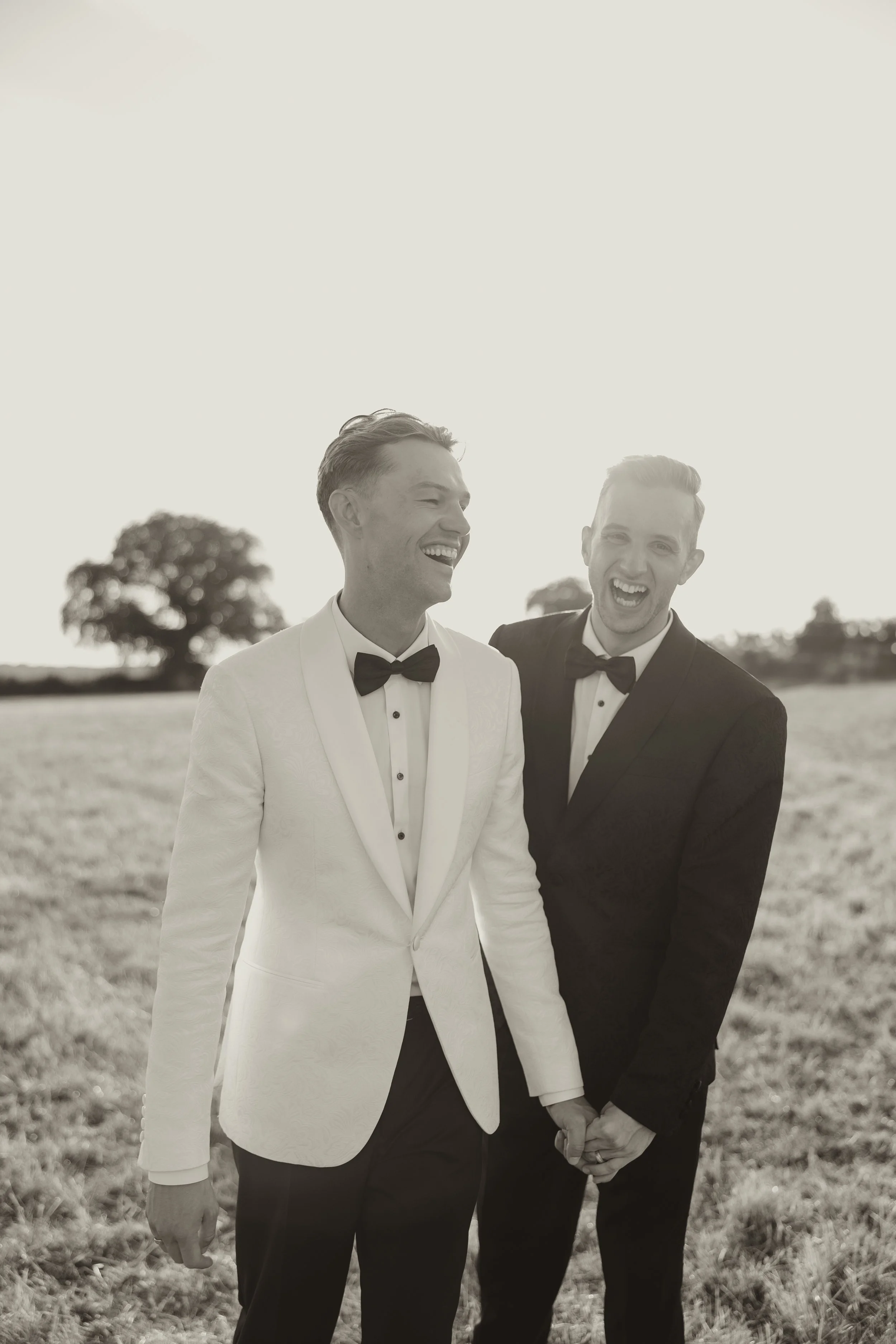 male gay couple on their wedding day in contrasting white and black suits with bowties captured in a natural editorial wedding photography style