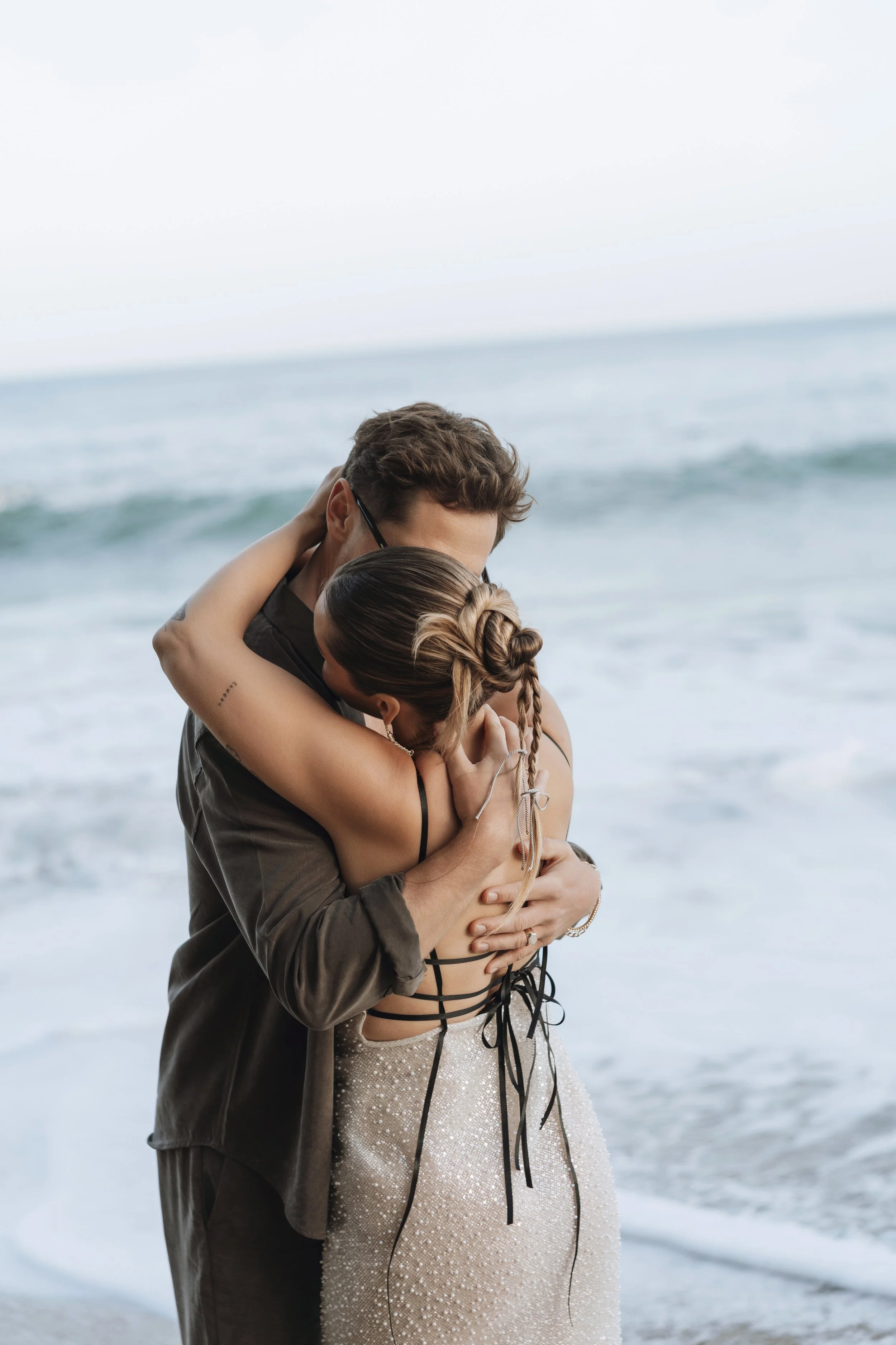 Romantic moment of couple embracing by the ocean during a destination pre-wedding shoot in Biarritz, soft natural light and editorial styling