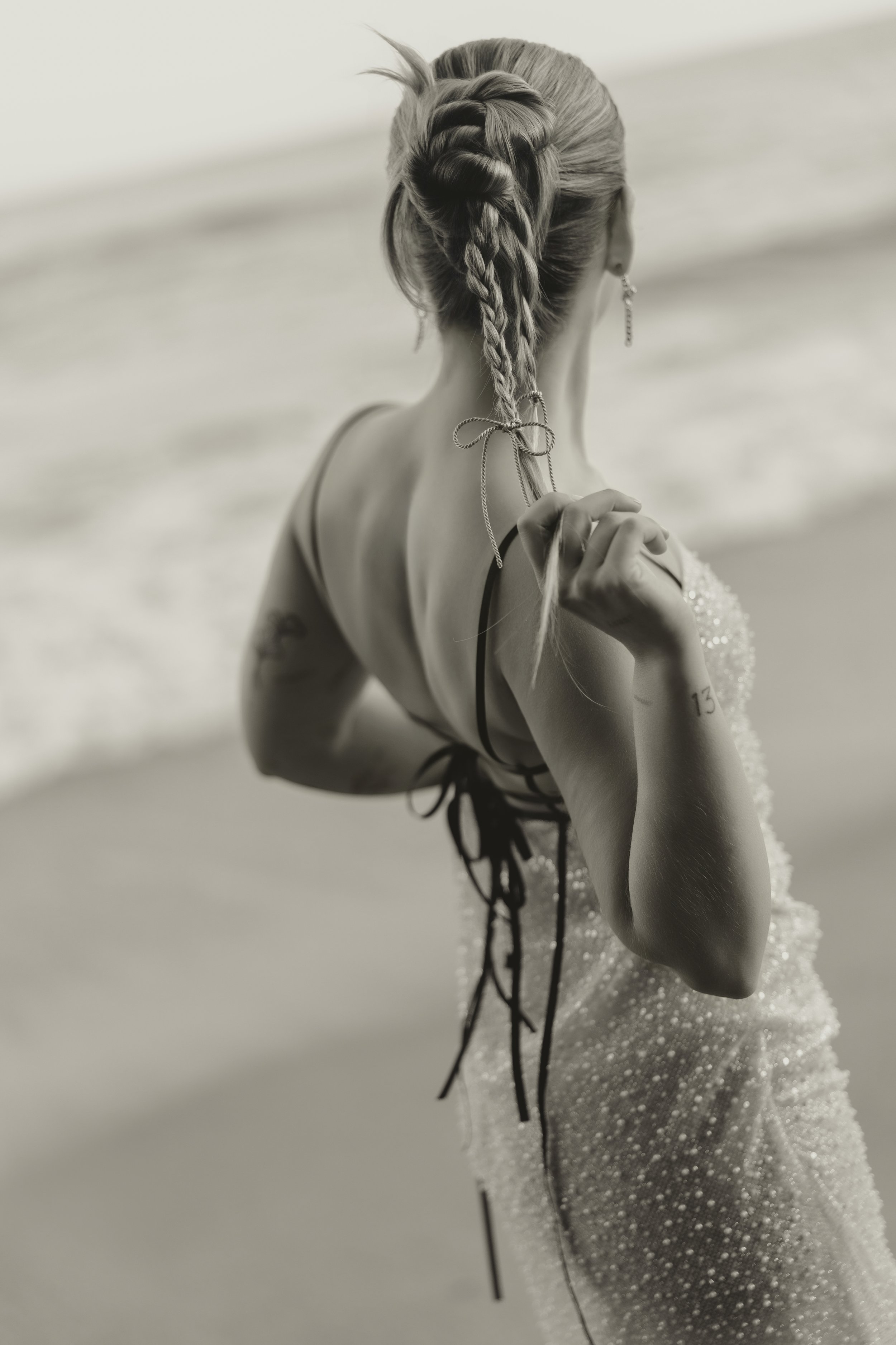 Close-up of bride’s braided hairstyle with ribbon detail and open-back embellished dress, editorial pre-wedding shoot by the sea in Biarritz