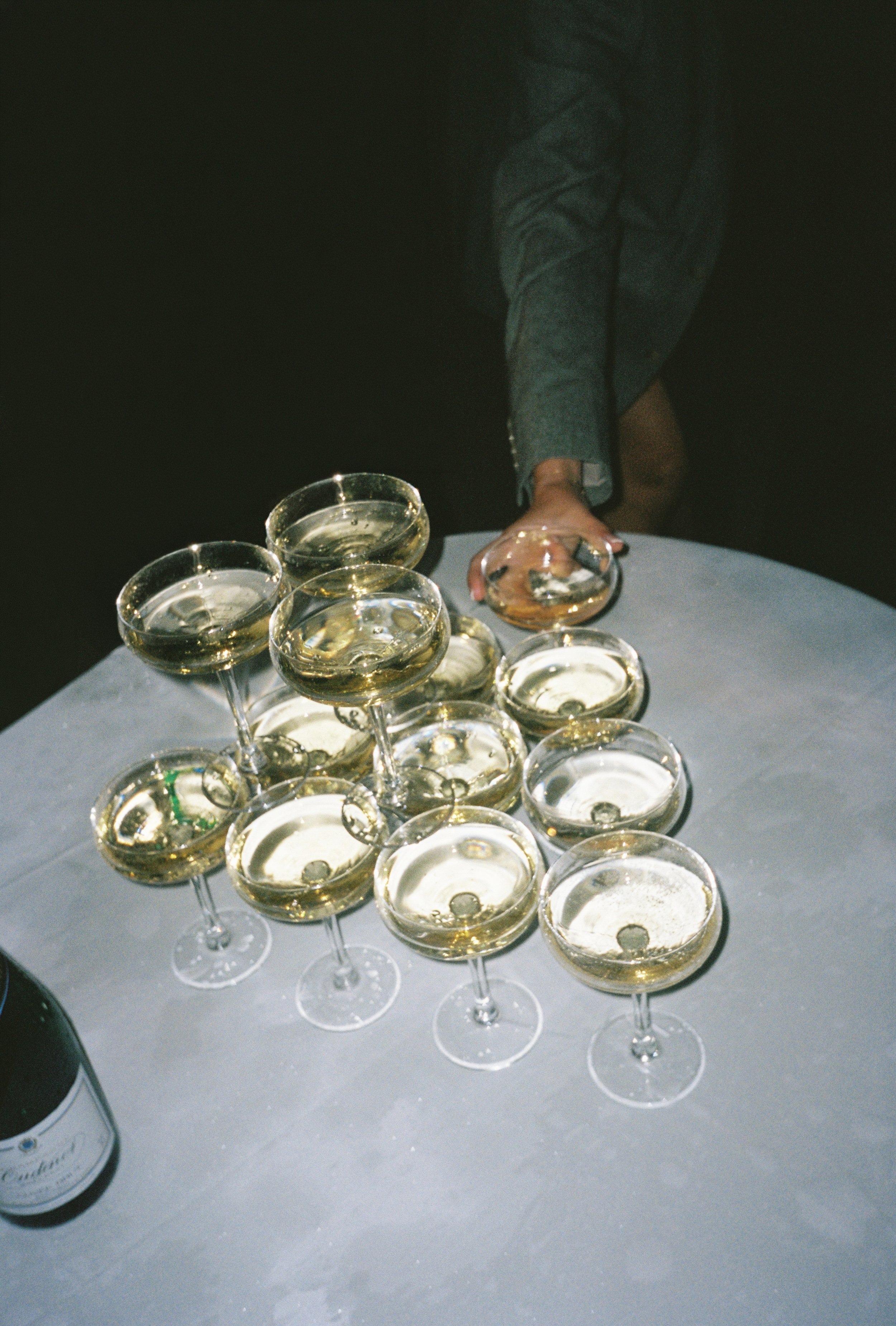 candid 35mm image of wedding guest taking a glass of champagne from a champagne tower at middleton lodge