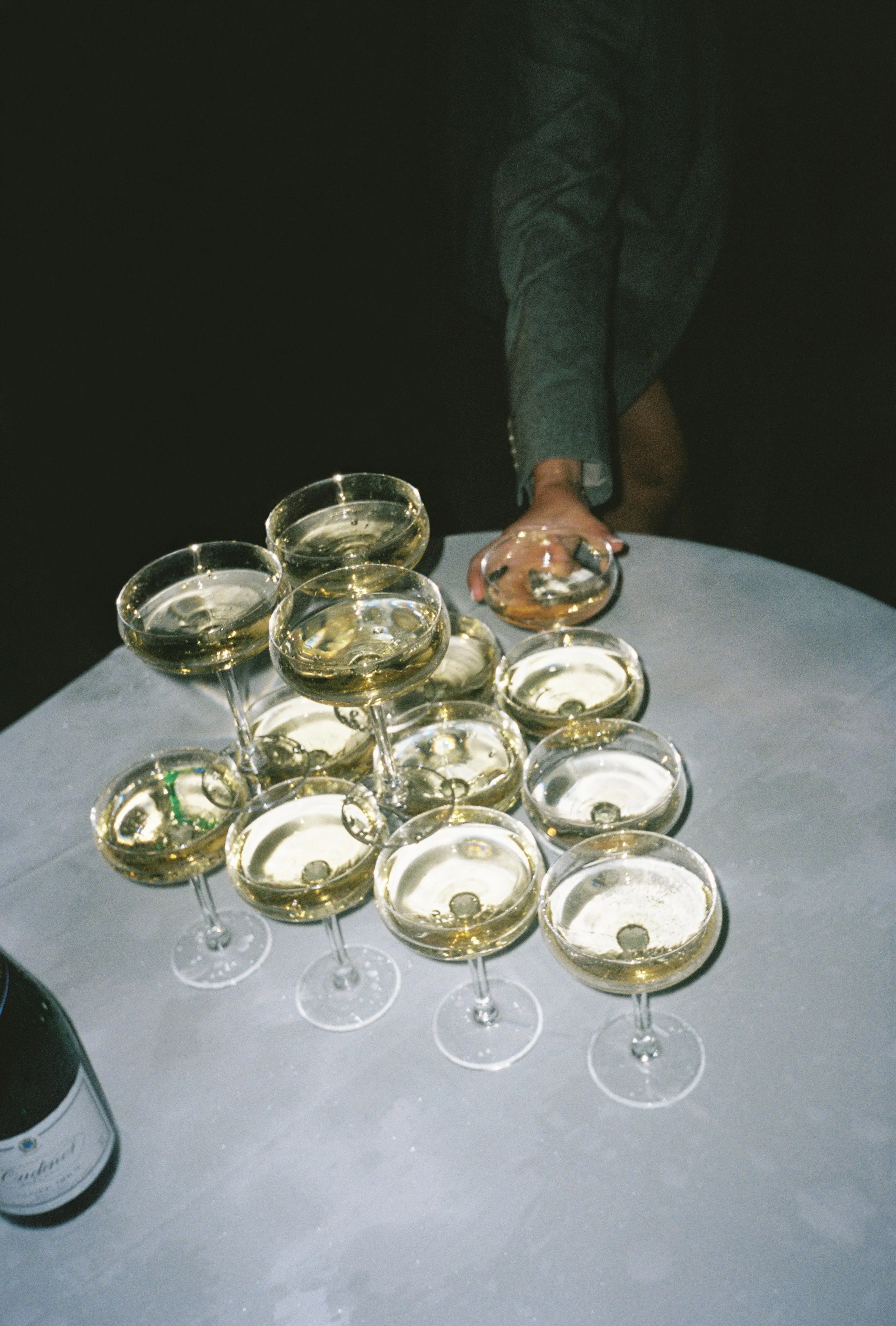 Candid wedding moment of guest and champagne tower captured on 35mm film with flash and gentle grain