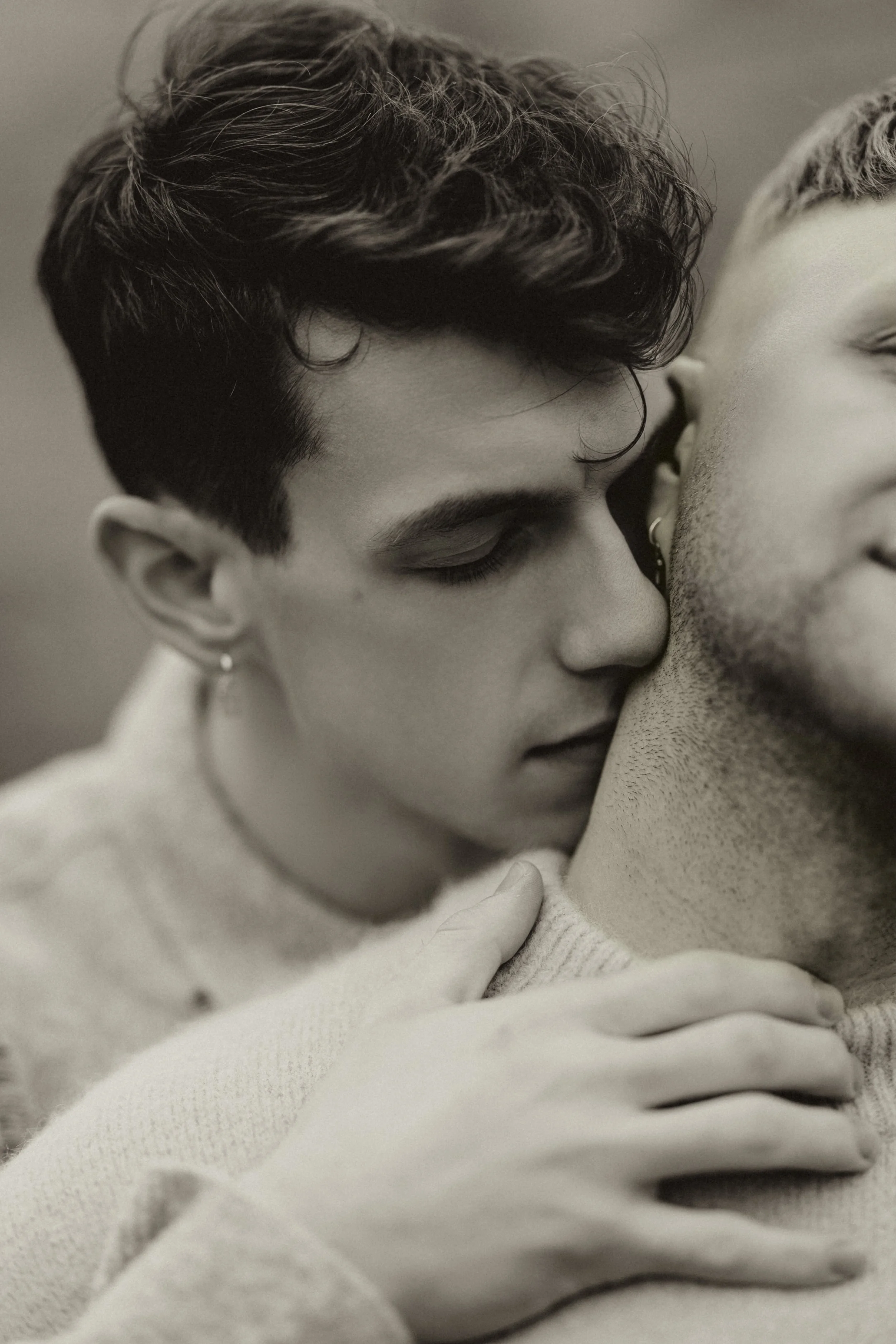 Intimate editorial portrait of a gay couple embracing, capturing soft, emotional connection in a modern, fashion-inspired wedding photography style