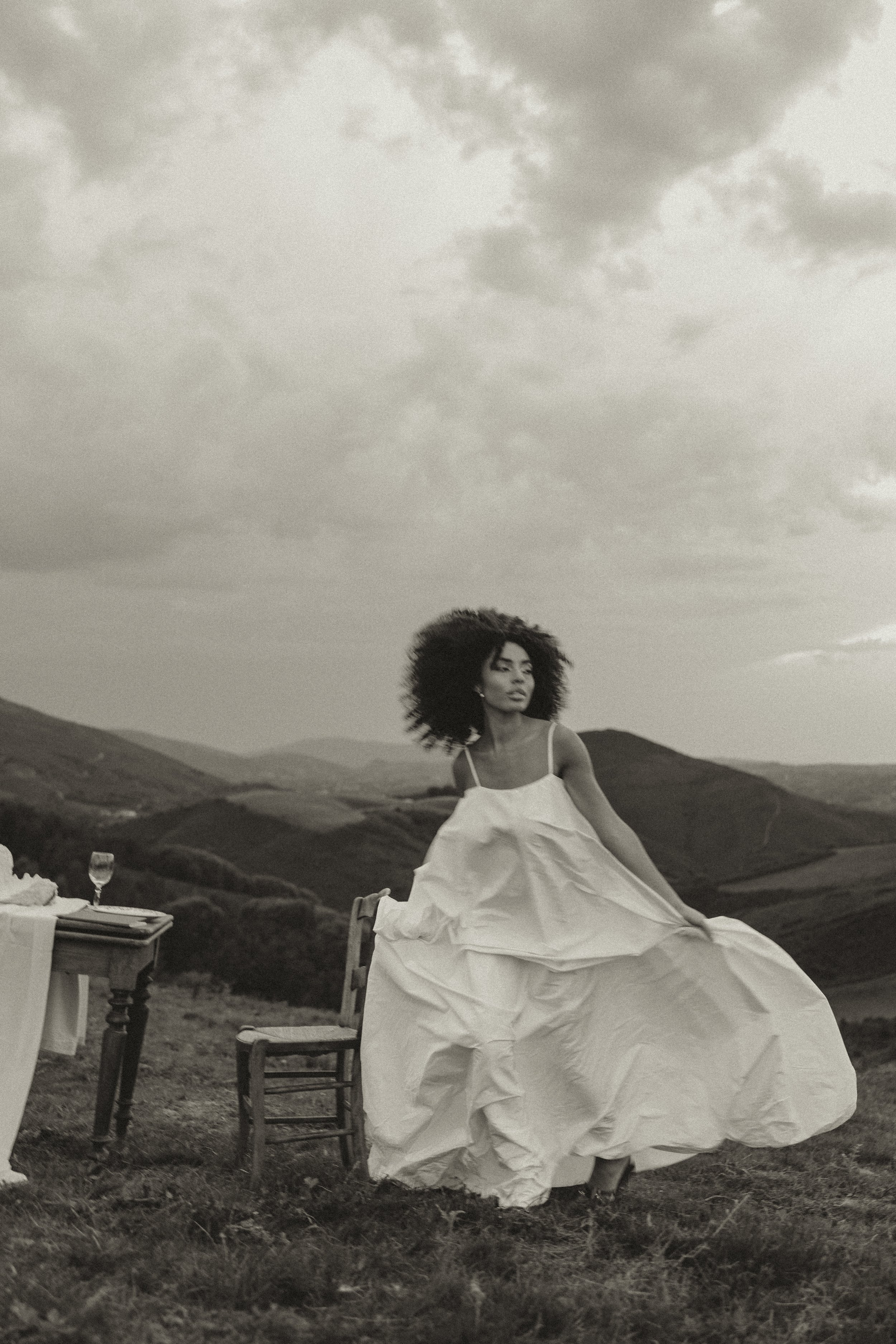 Editorial bridal portrait of a modern bride in a flowing wedding dress set against a mountain landscape, captured in a fashion-inspired destination wedding style