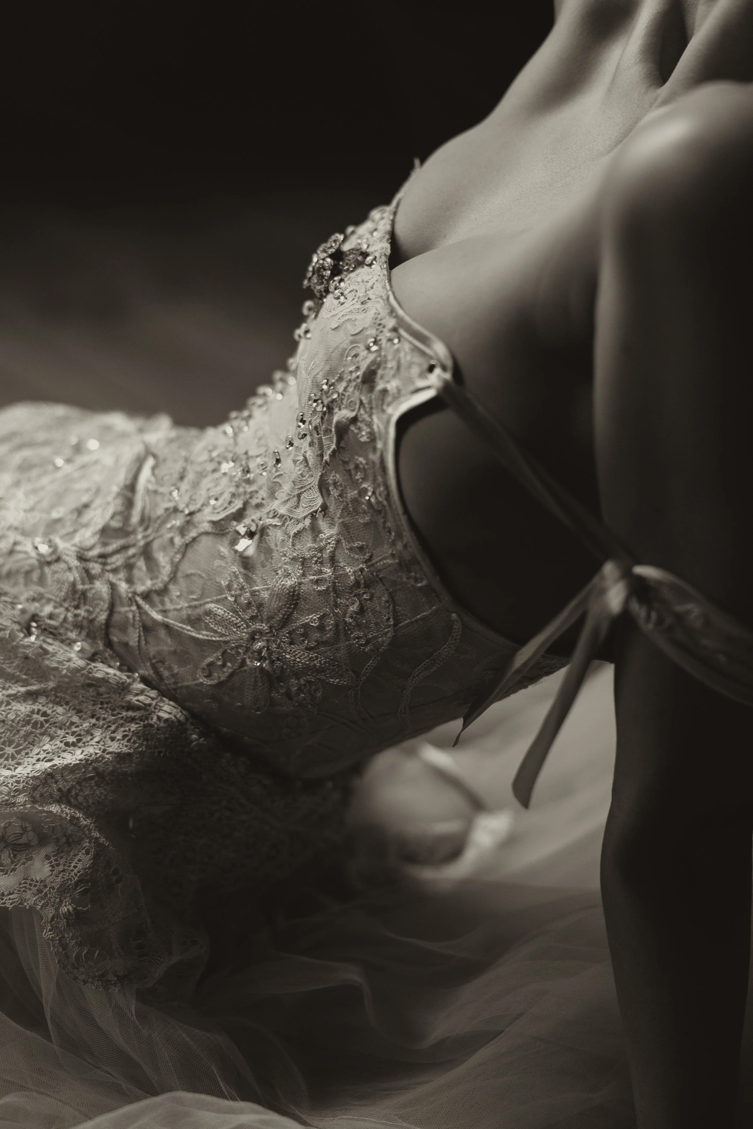 Close-up of a woman in a lace wedding dress, lying down, captured in black and white.