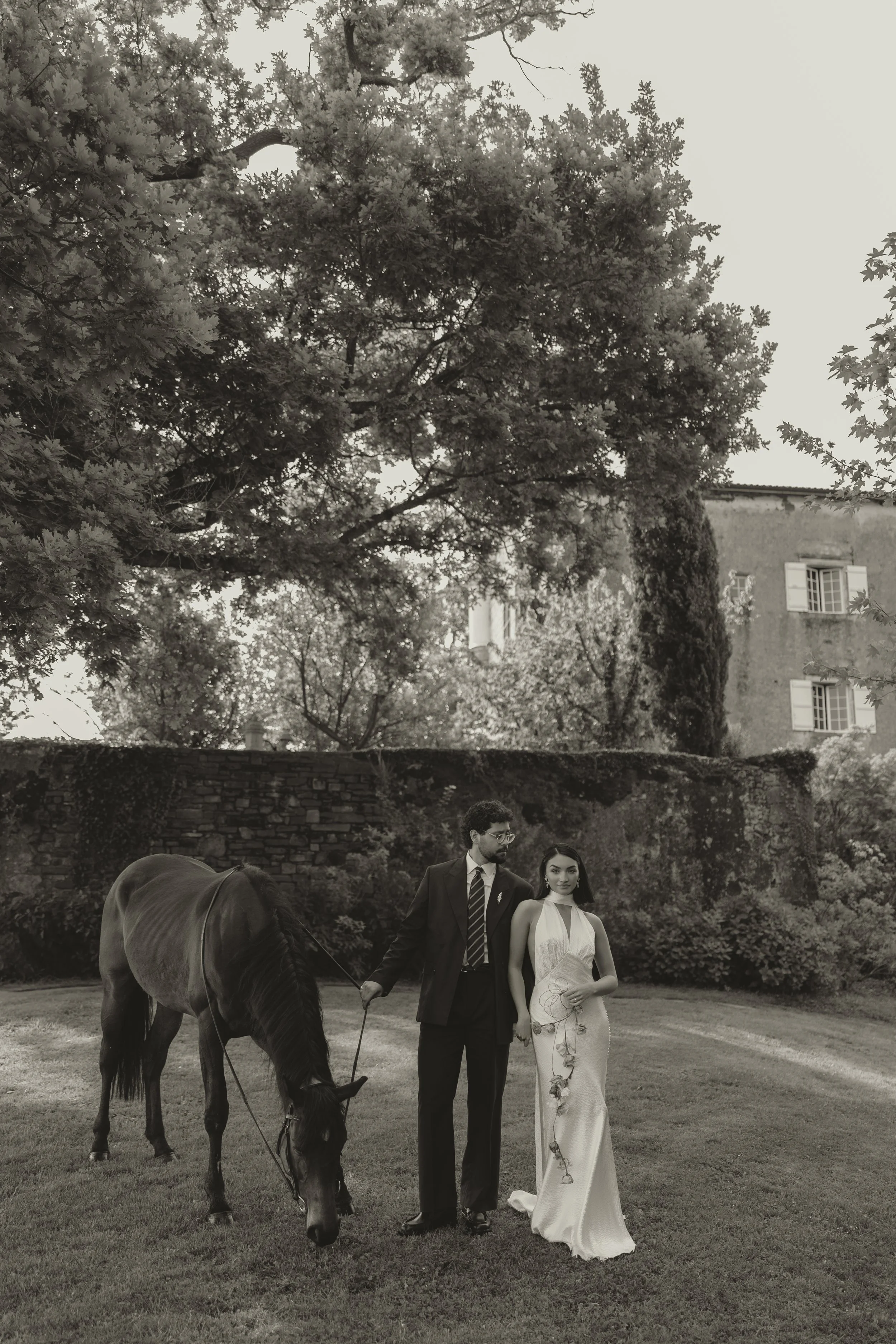 Editorial wedding portrait of a bride and groom with a horse in the gardens at Maison Belzunce, a château wedding venue in southwest France.