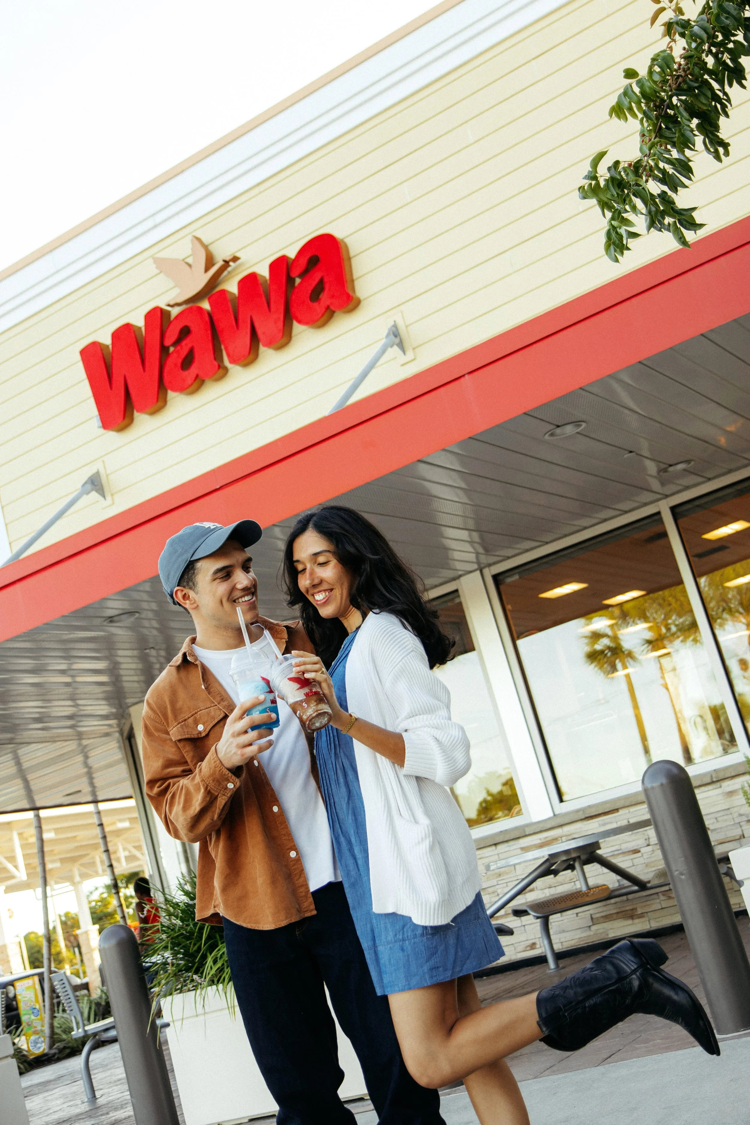 A young couple is standing outside a Wawa convenience store. They hold slushies and they smile at each other during a Creative Couples Photography Session