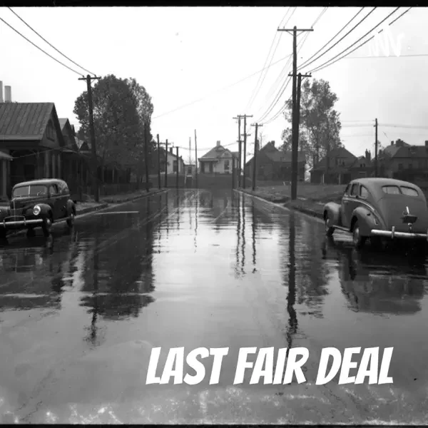 A black-and-white photograph of an empty wet street with vintage cars parked on either side and telephone poles lining the street, with the text "Last Fair Deal" at the bottom.