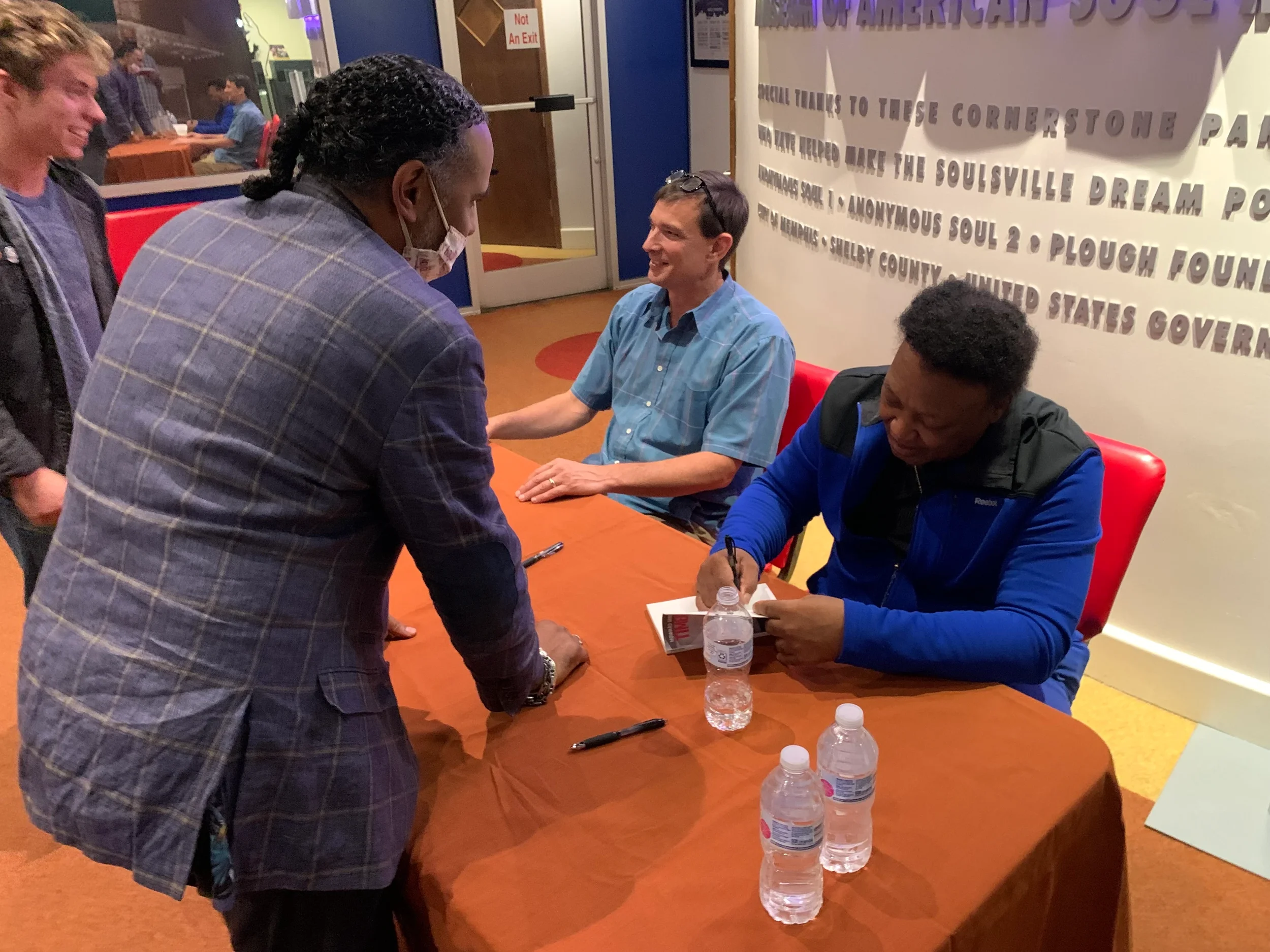 preston Lauterbach and Howard Grimes sign a book for Boo Mitchell, Willie Mitchell's son