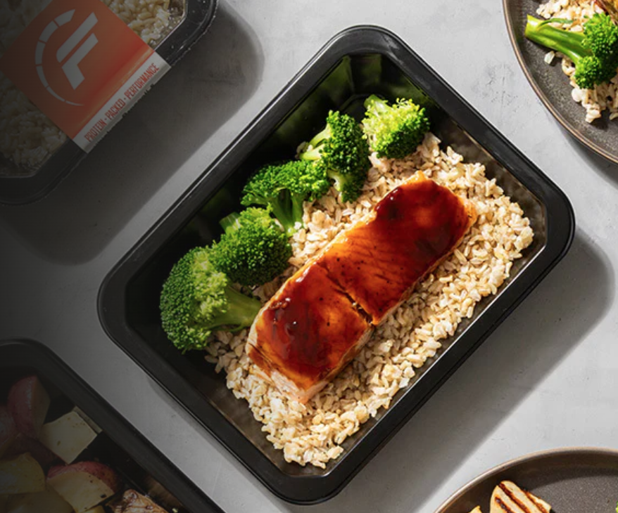 Prepared meal with salmon fillet glazed with sauce, served on bed of rice with broccoli florets.