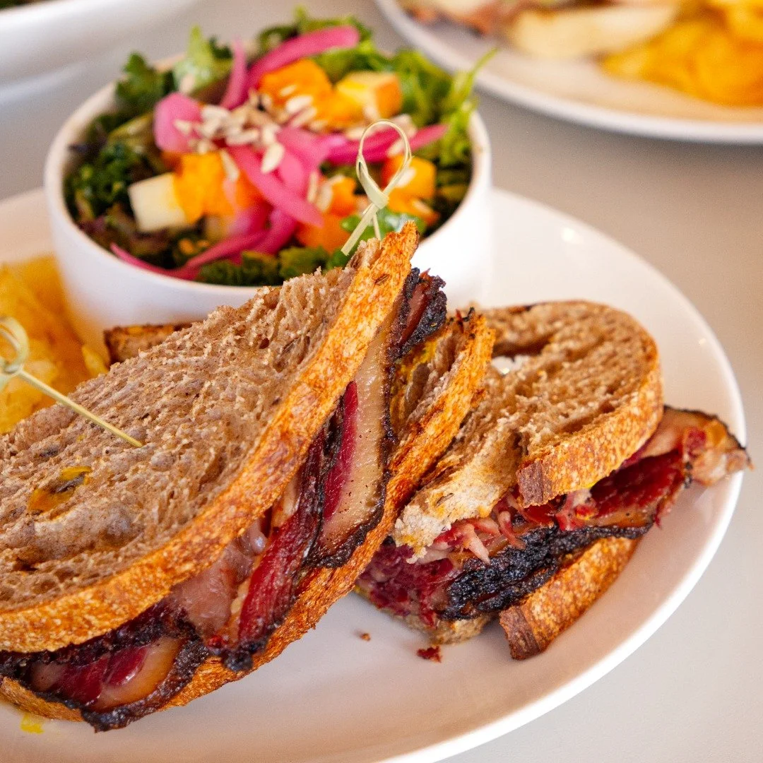 House-smoked brisket stacked high with yellow mustard and a classic dill pickle (comes with kettle chips, pickles, and your choice of side salad) best paired with a classic diner mug drip coffee or an iced americano to cut through that richness!