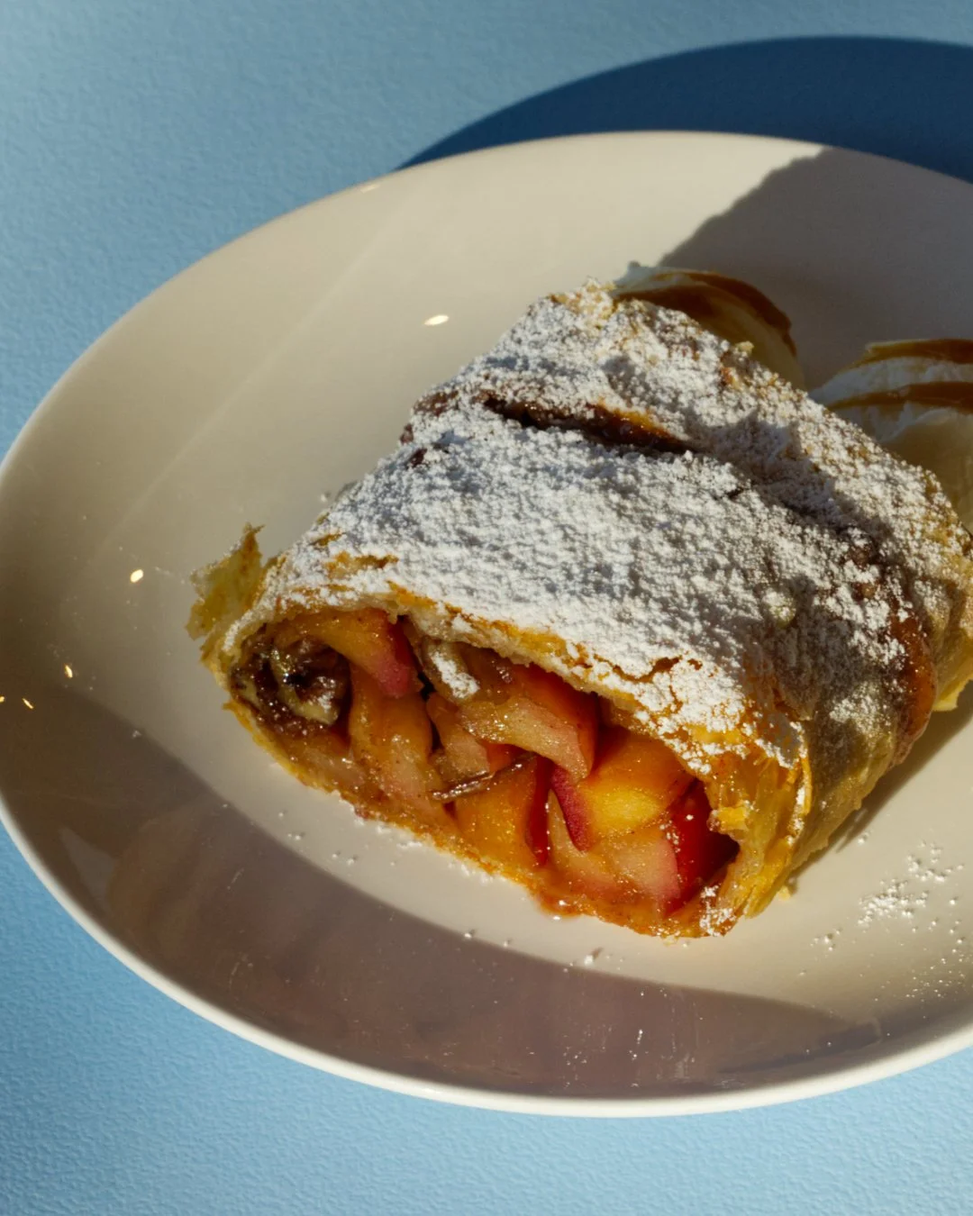 Flaky pastry, warm cinnamon apples, a snow of powdered sugar 

Our apple strudel is on the menu, and it&rsquo;s the kind of dessert that makes you stay for another coffee