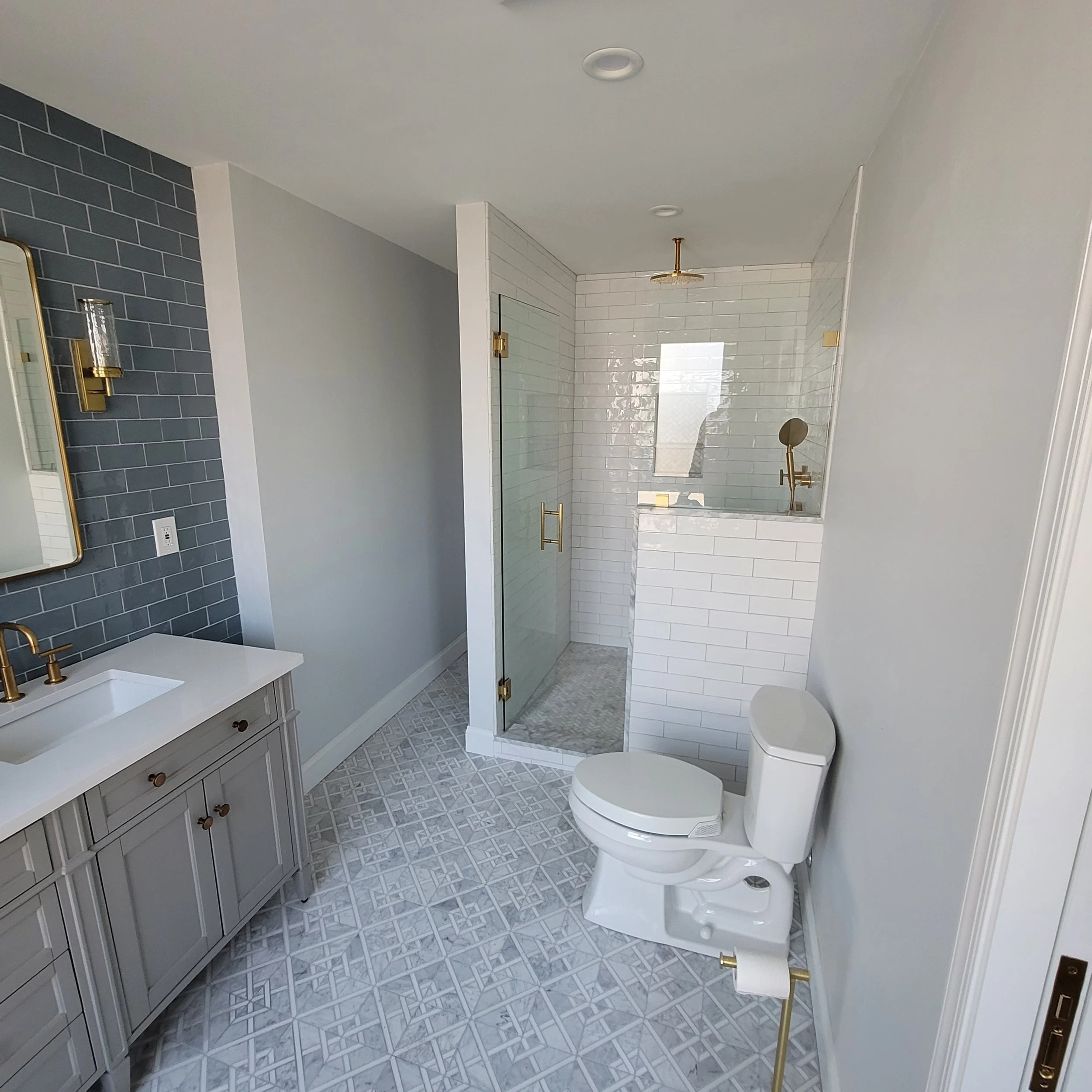 Modern bathroom with a vanity, a toilet, and a tiled shower area with glass door.