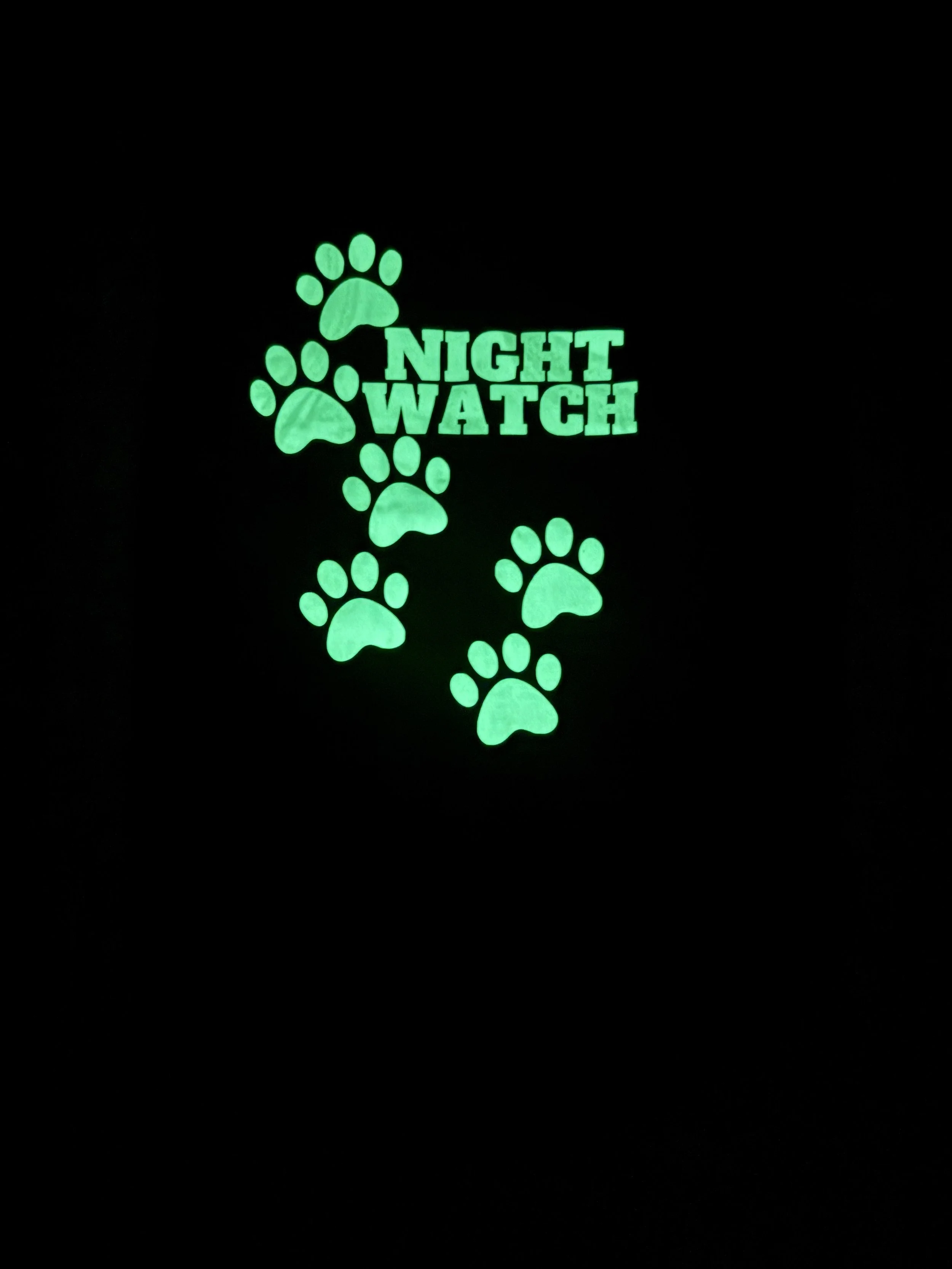 Glow-in-the-dark dog shirt with paw prints and Night Watch graphic on black polyester fabric