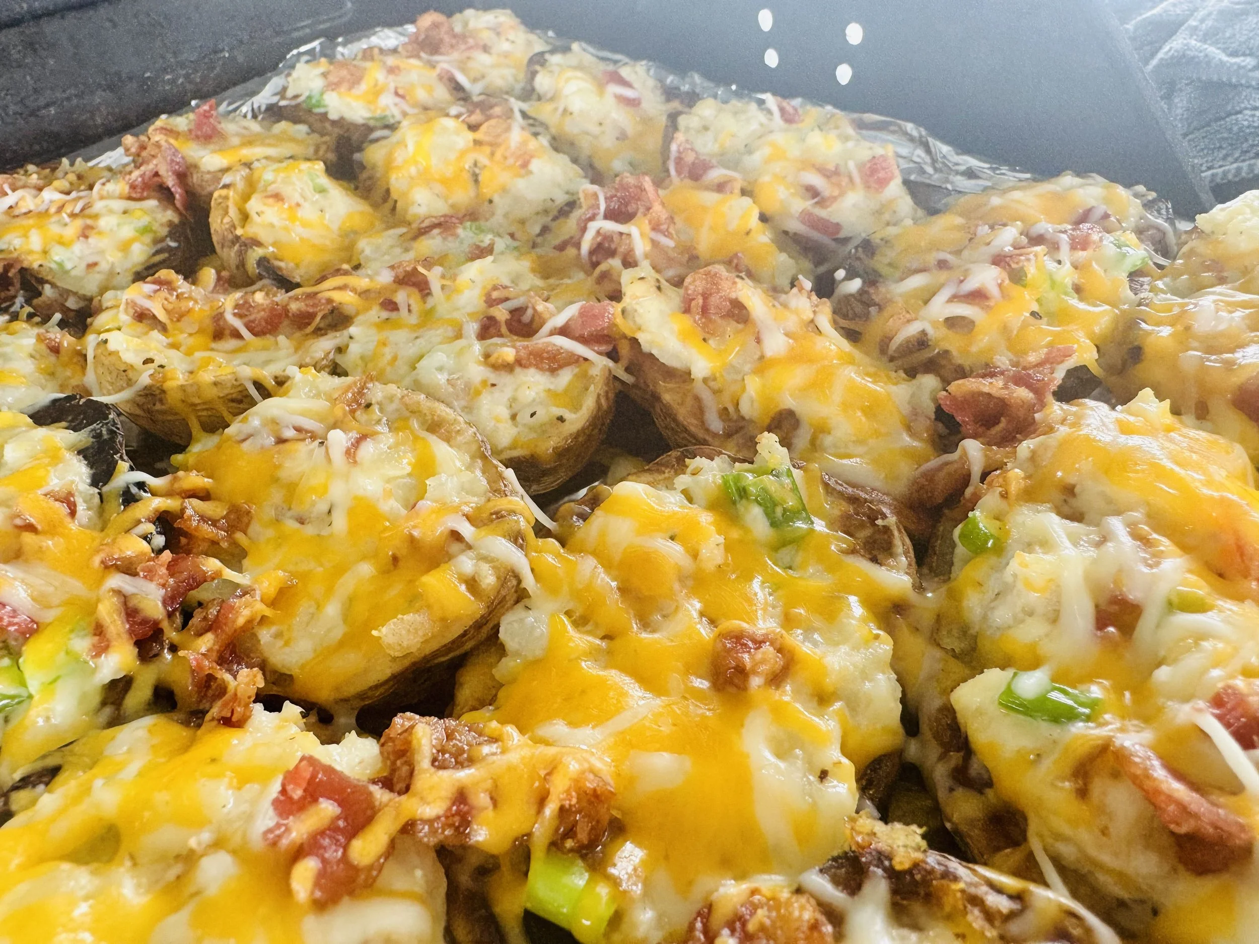 Grilled potatoes with sour cream, cream cheese, scallions, cheese and topped with bacon and cheese