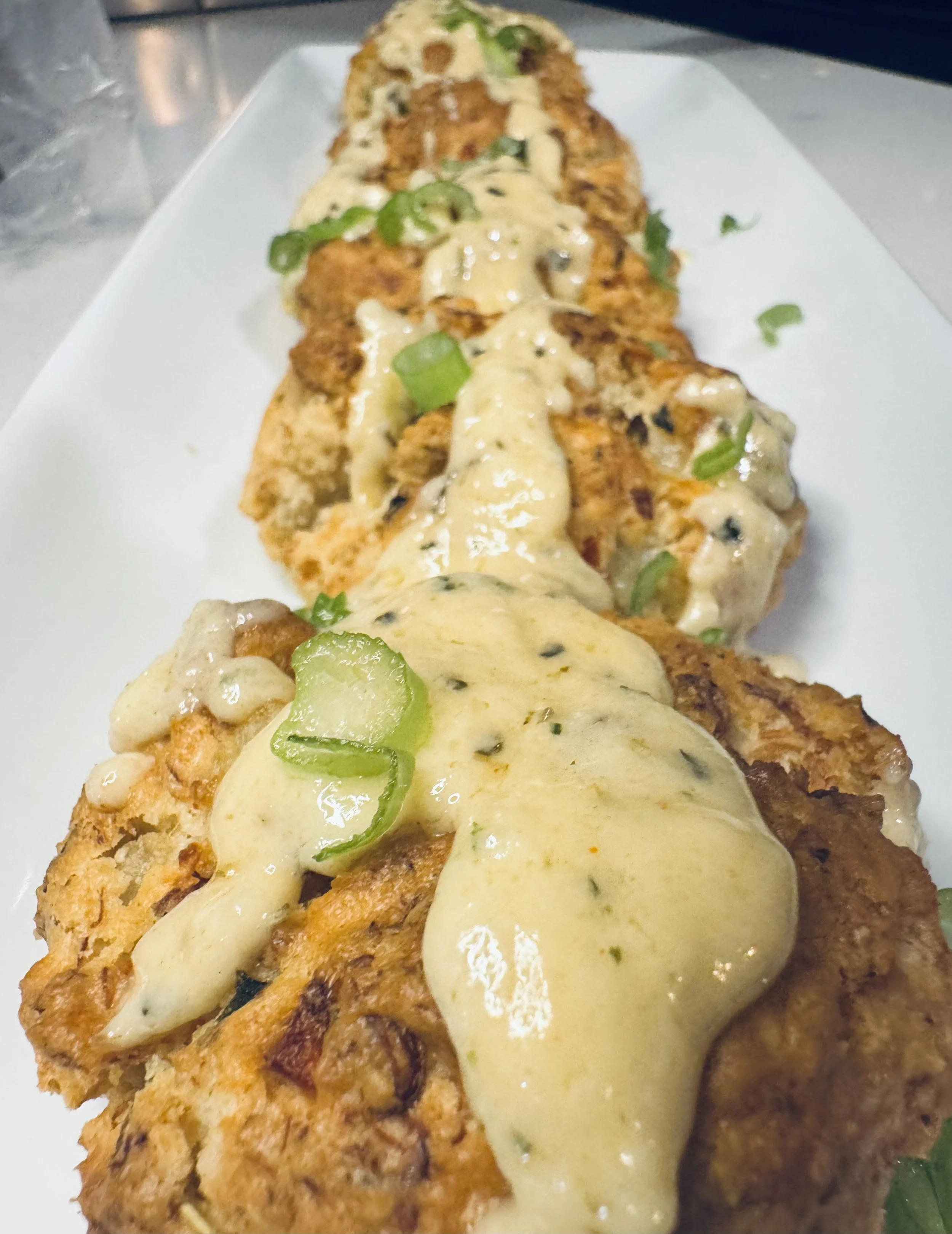 Seafood cheddar bay biscuits topped with creamy Romano sauce and green onions