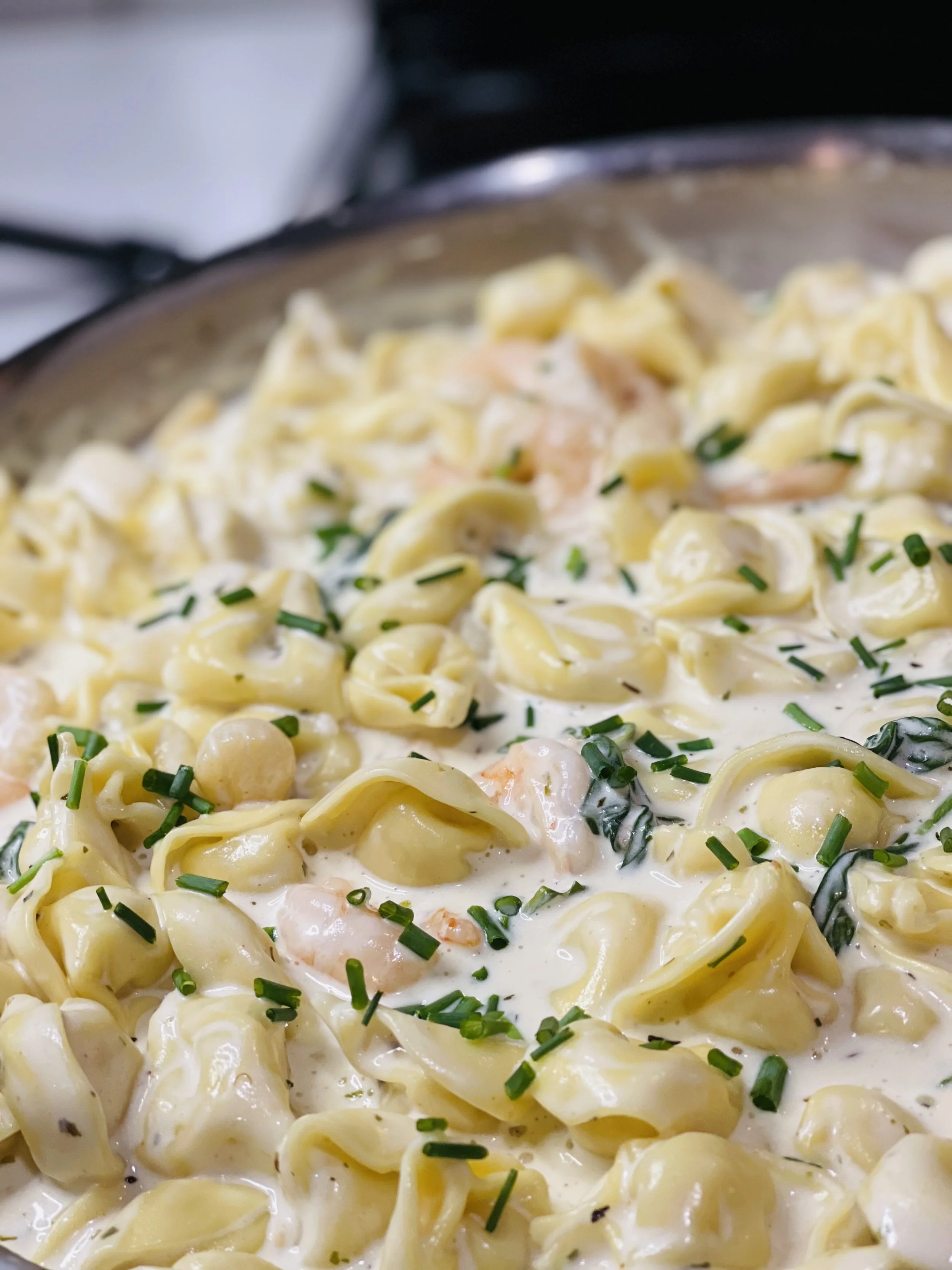 Creamy shrimp and scallops tprtellini topped with herbs in a rich cream sauce