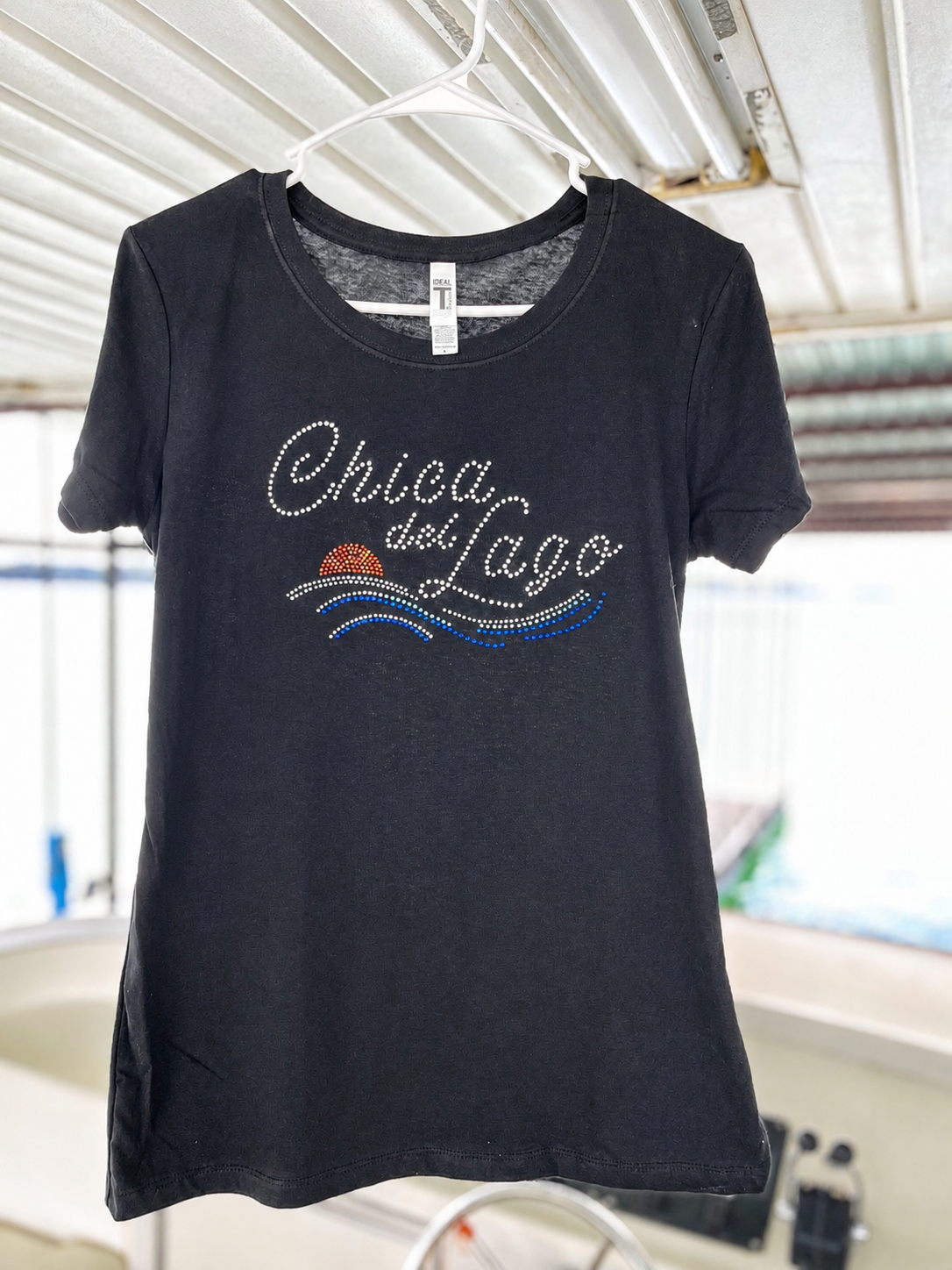 Camiseta negra ajustada para mujer con diseño de rhinestones “Chica del Lago” y detalles de atardecer y olas coloridas estilo lake life.