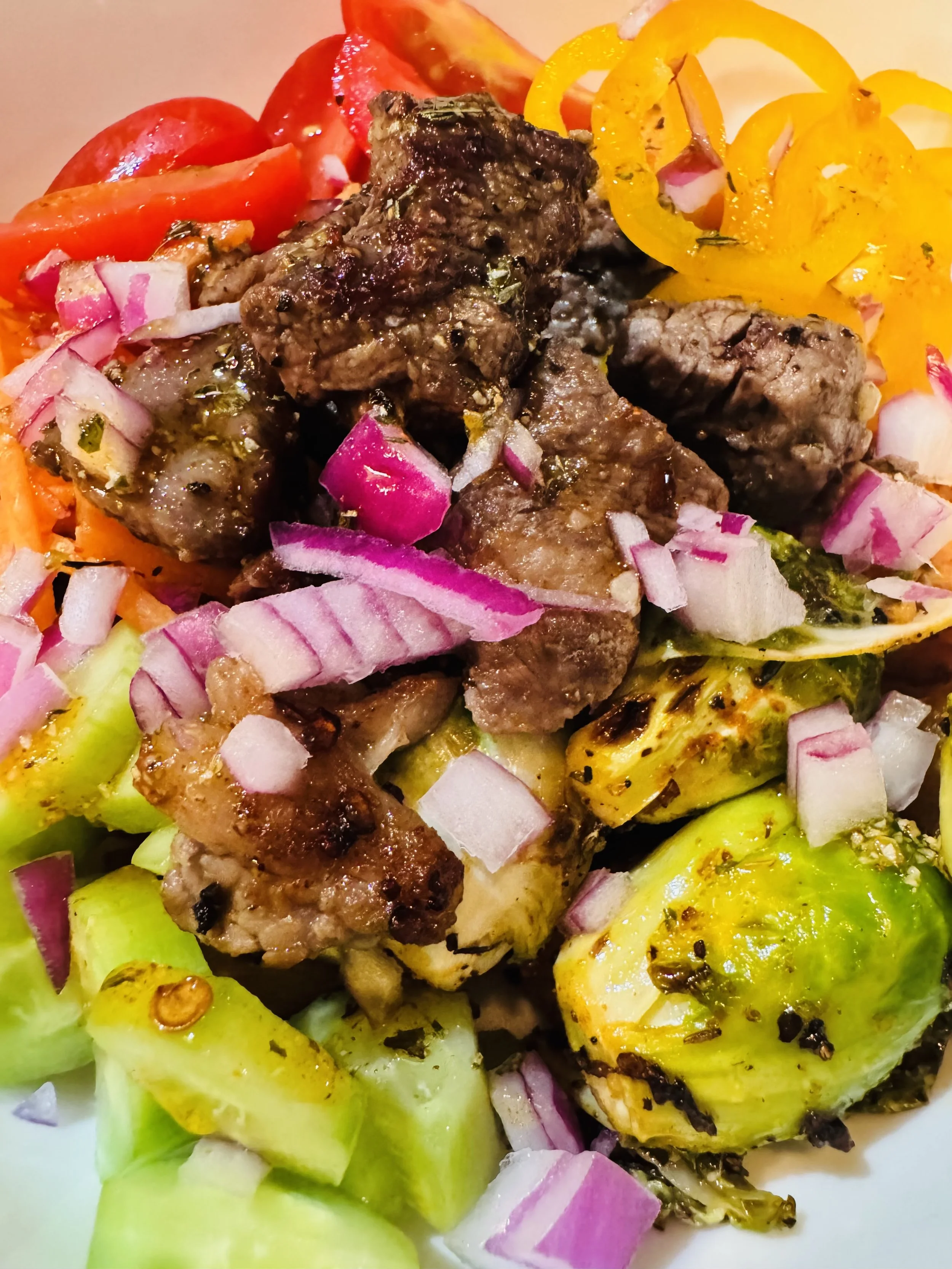 Steak bowl with roasted veggies, avocados, mini peppers, tomatoes, red onions and served with seasoned olive oil