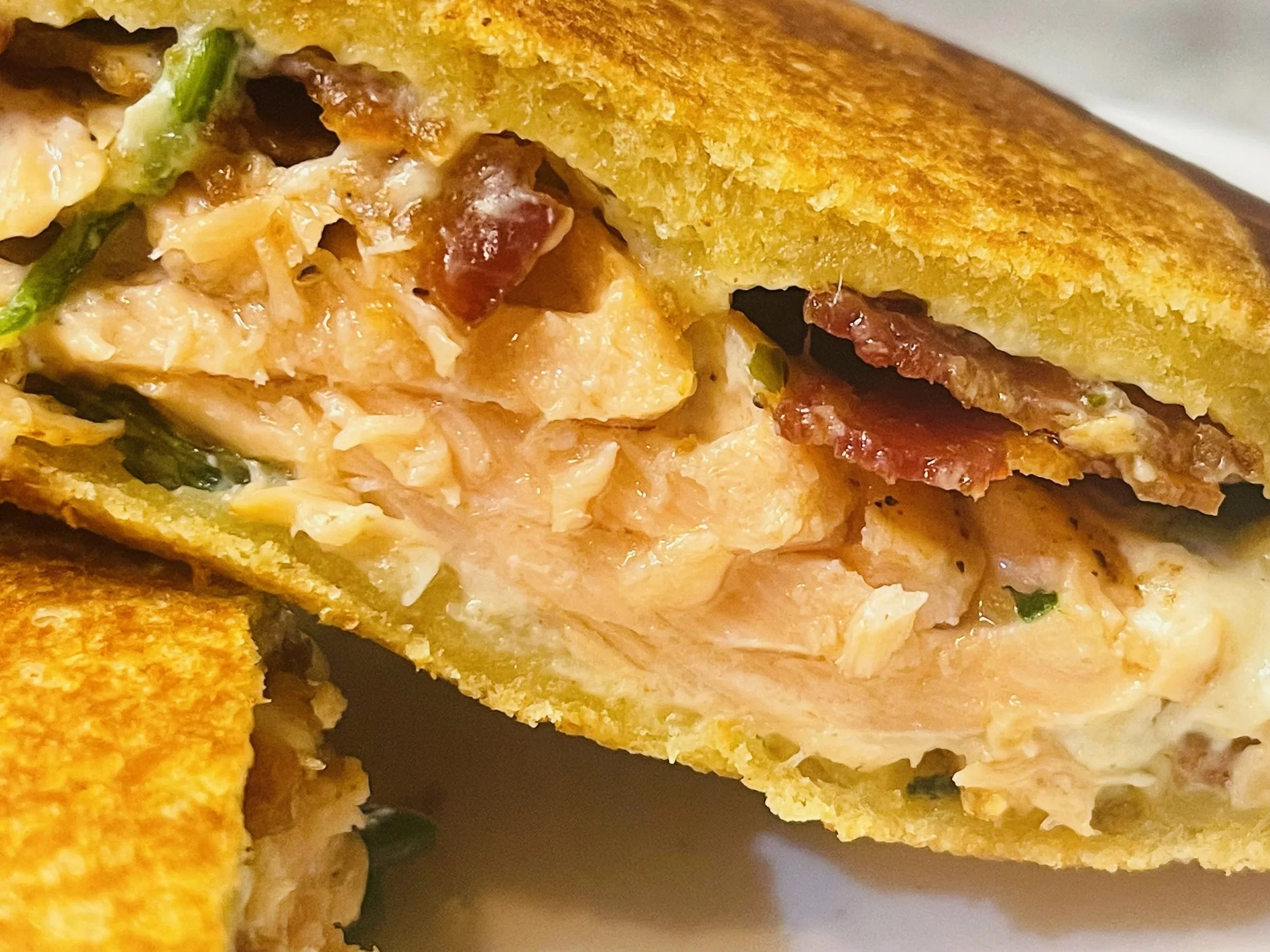 Sauteed salmon with bacon and cream cheese spinach spread on brioche bread