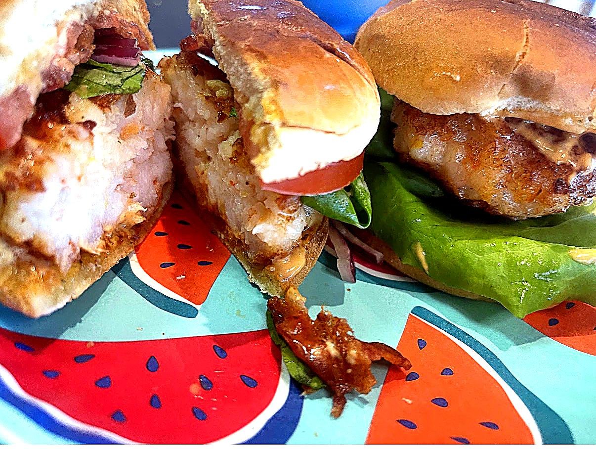 Crispy shrimp sliders with lettuce, tomato, red onions, bacon and creamy sauce on toasted buns