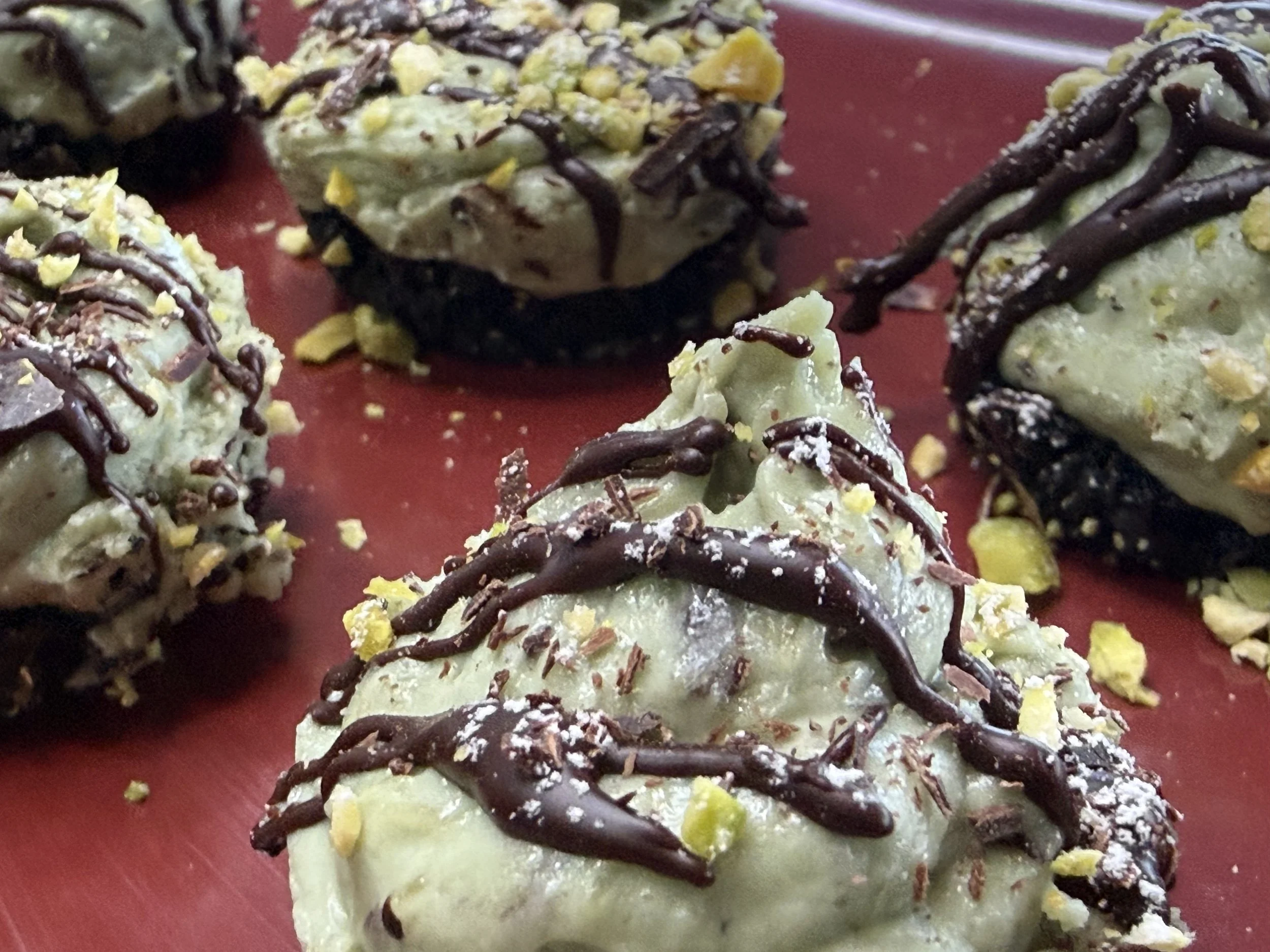 Bite-sized pistachio cheesecakes with Oreo crust and dark chocolate drizzle