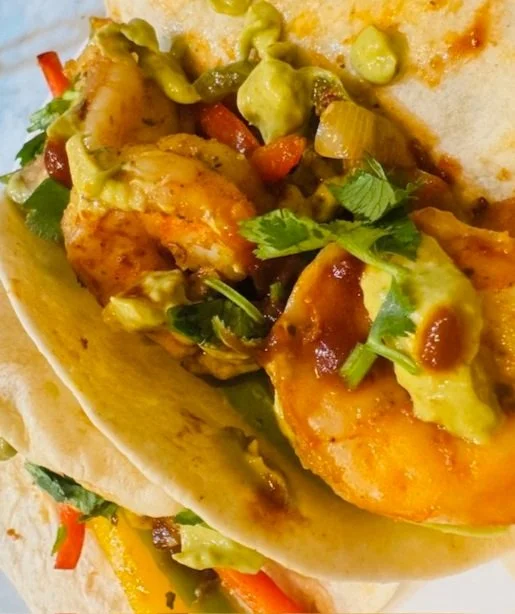 Shrimp, peppers and onions in a warm tortilla shell topped with avocado cream sauce