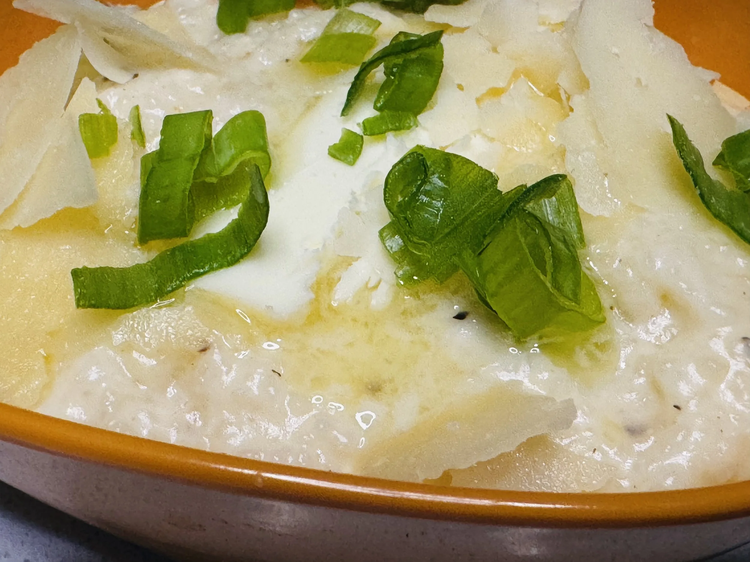 Creamy cheesy grits topped with parmesan cheese, green onions and butter