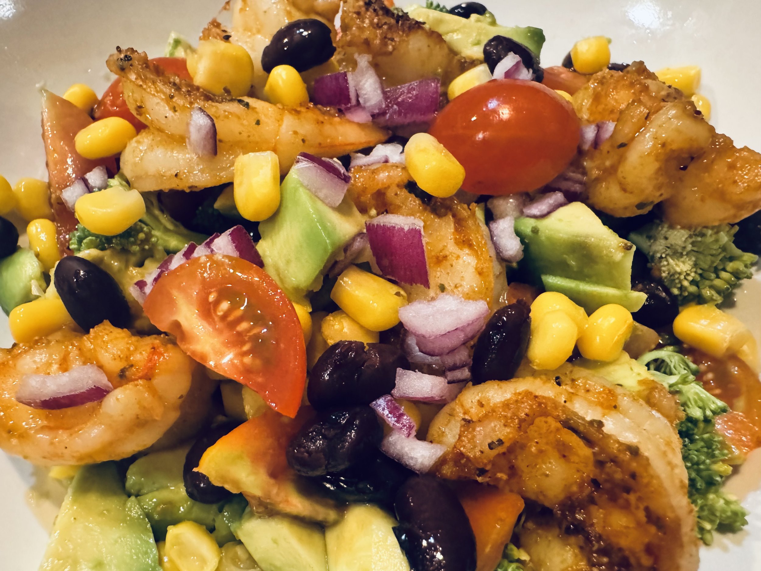 Shrimp salad with avocado, black beans, tomatoes, corn, broccoli served with a seasoned olive oil dressing
