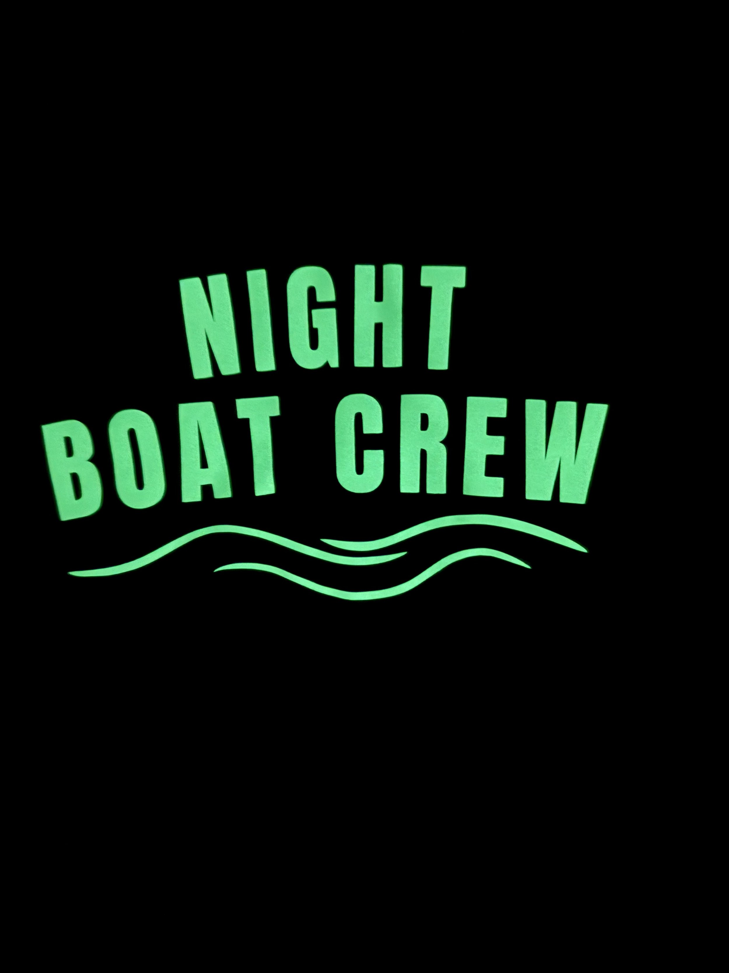 Night Boat Crew glow-in-the-dark ladies racerback tank top in navy blue featuring a glowing green boating graphic and wave design, perfect for lake life, dock parties, and night boating adventures.