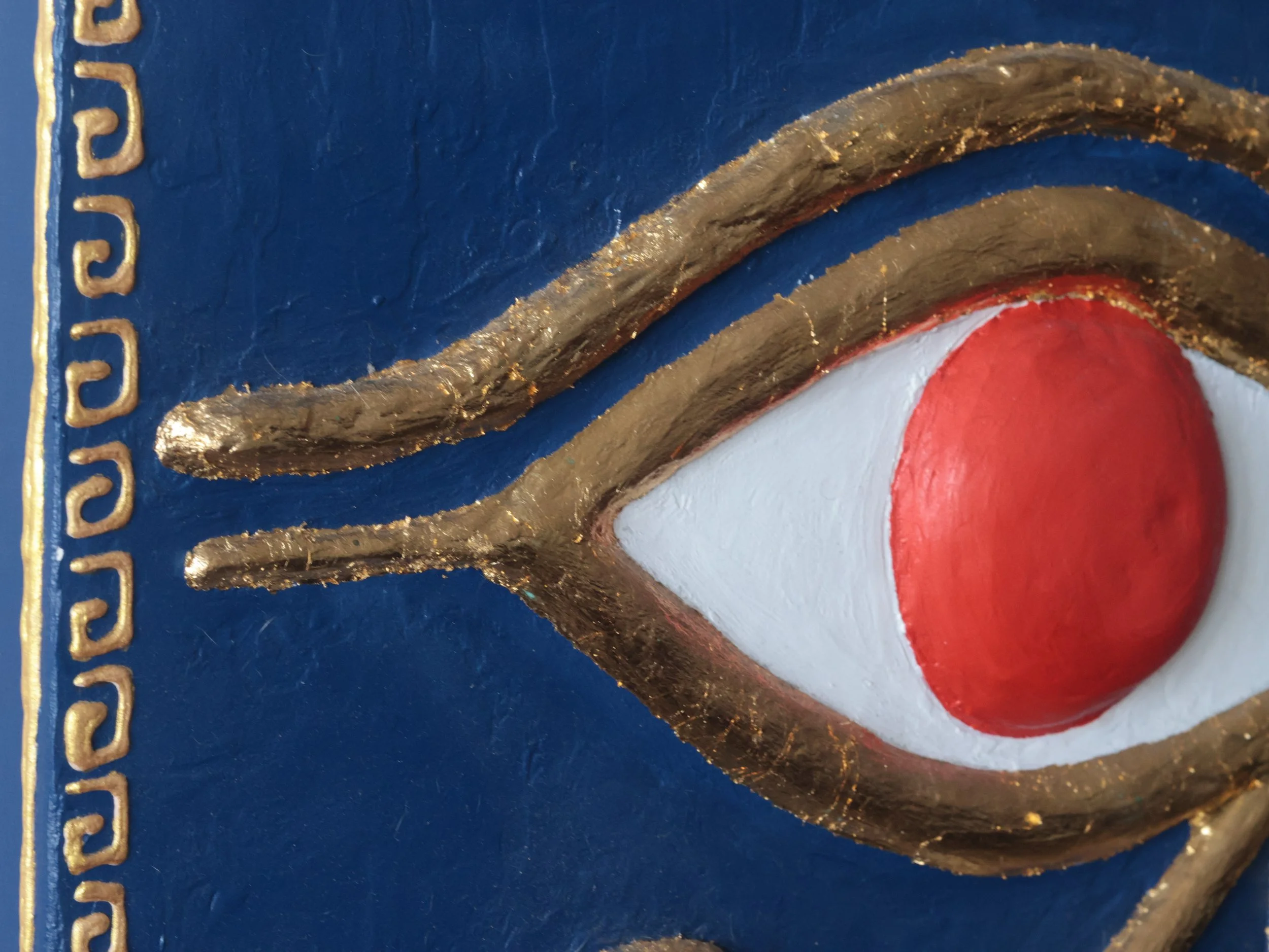 Close up, detailed image of gold leaf on an Eye of Ra painting.