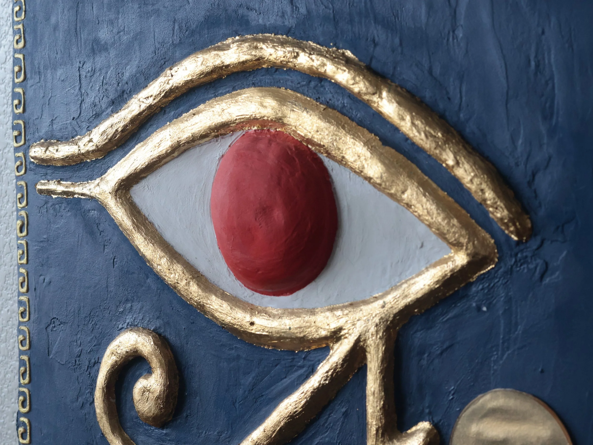 Different angle of an Egyptian art inspired Eye of Ra artwork hanging on a wall.