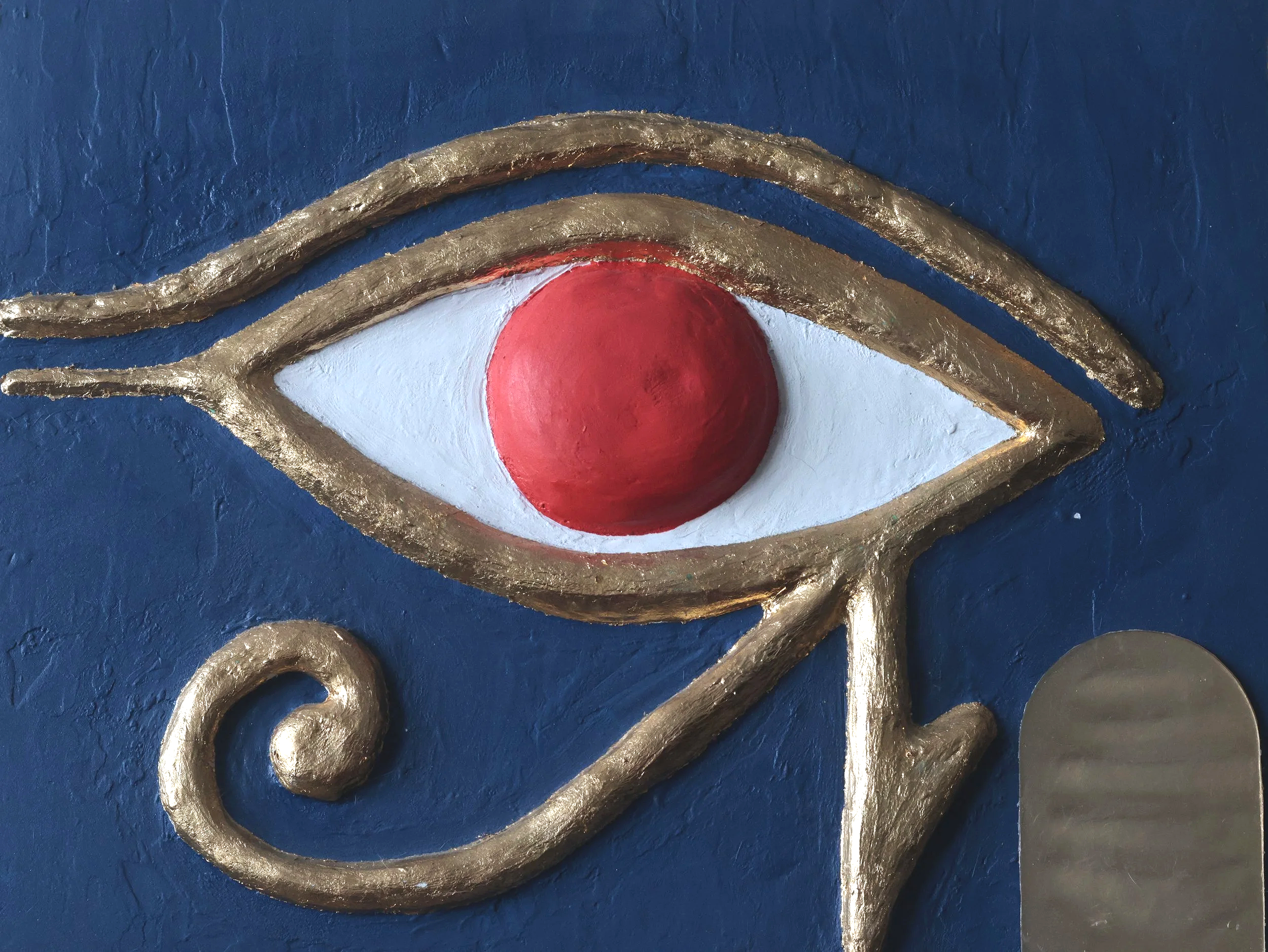 A front view photo of a textured Eye of Ra painting hanging on a wall.